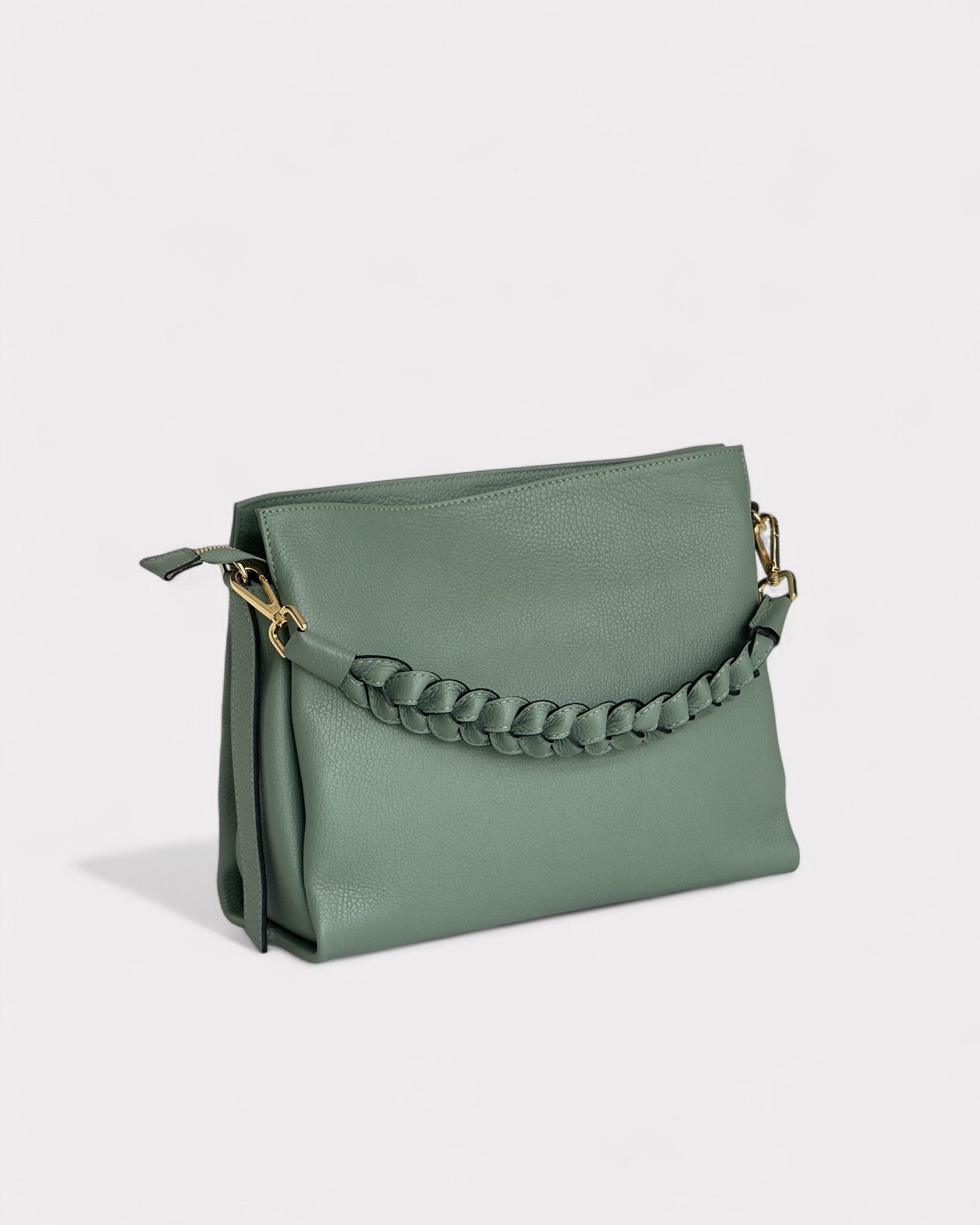 Green handbag with braided handle on a light gray background