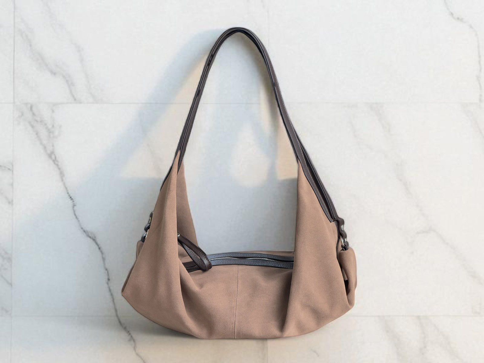 Taupe handbag with black accents on a light marble background