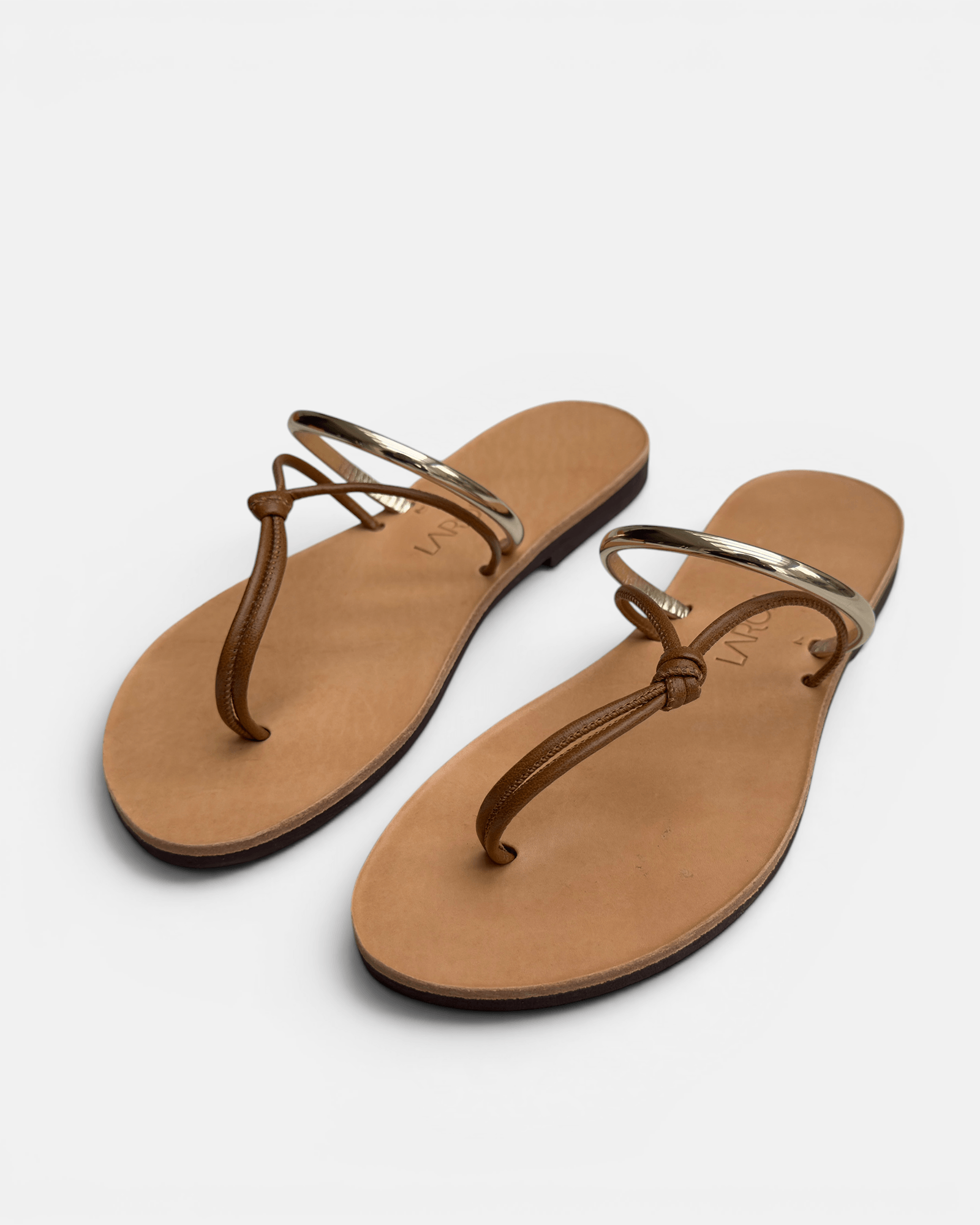 Pair of tan sandals with thin straps on a white background