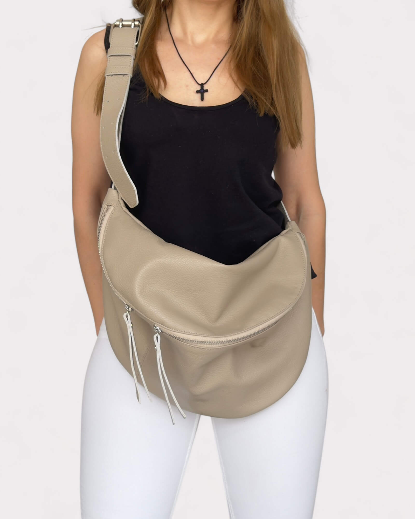 Person wearing a beige sling bag on a white background