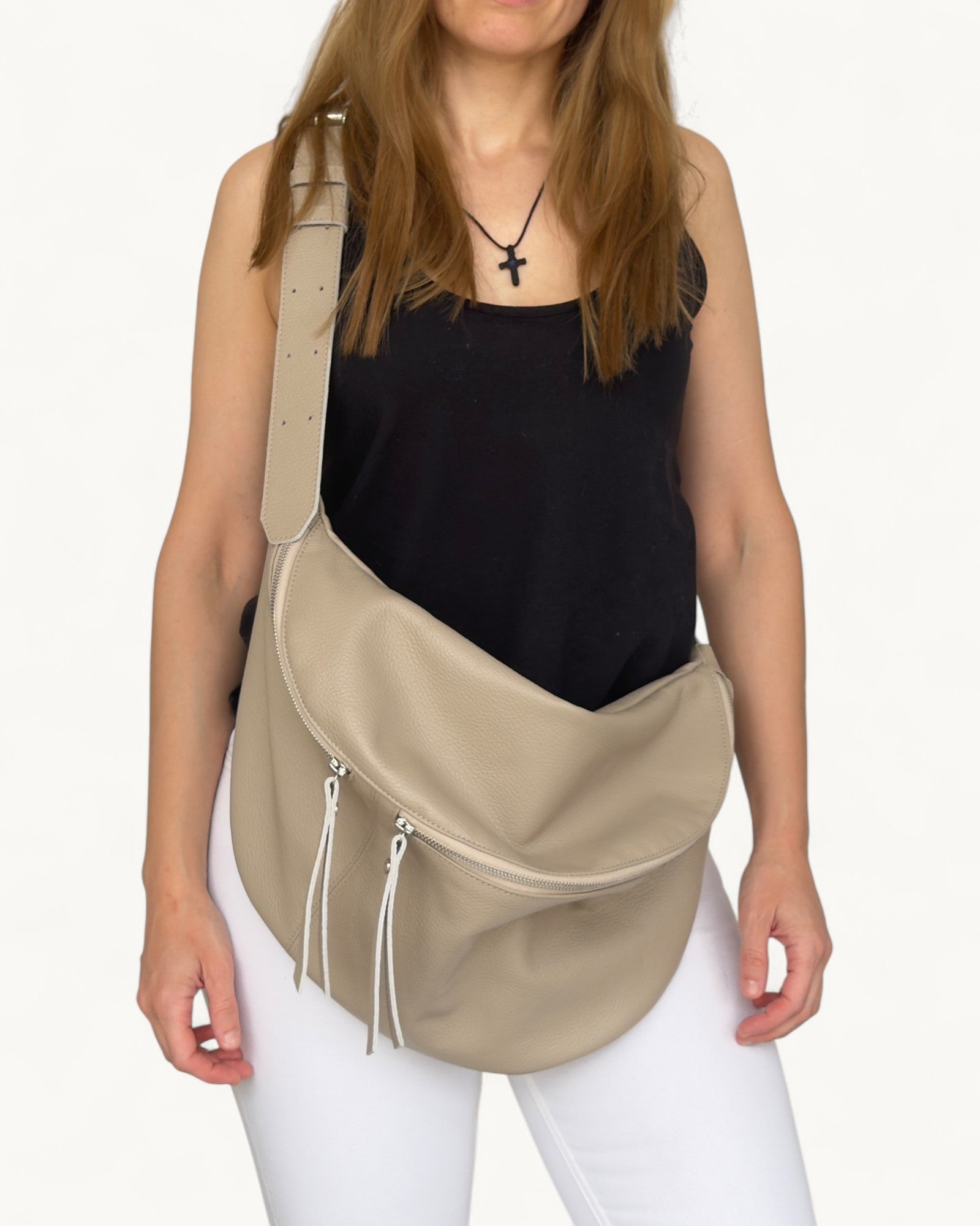 Woman wearing a beige crossbody bag on a white background