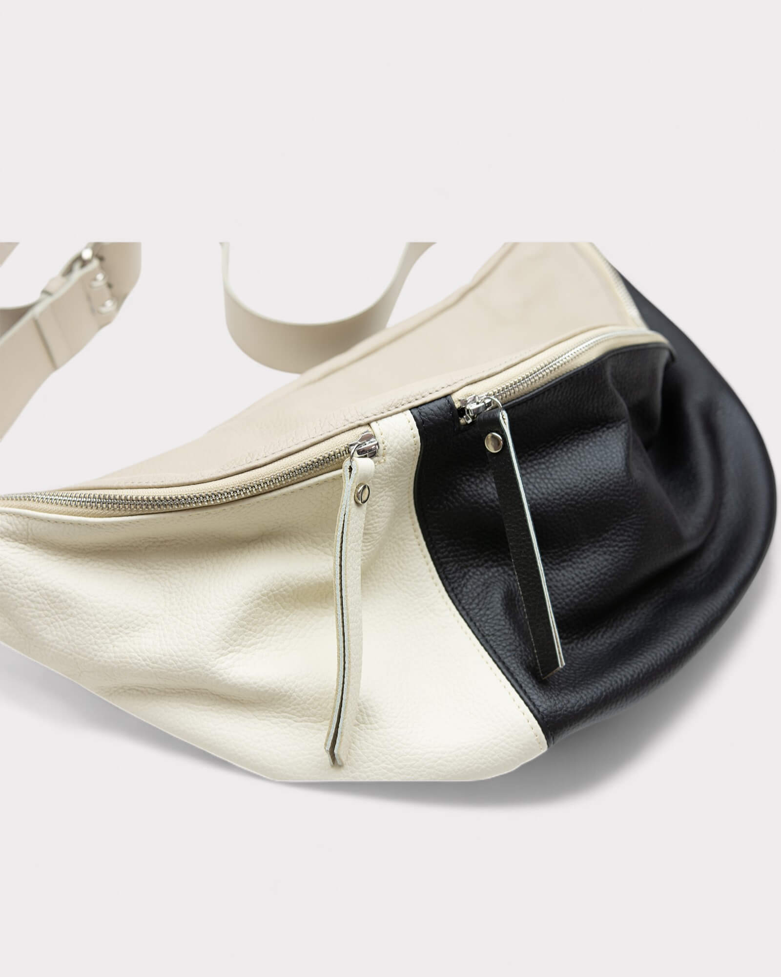 Two-tone beige and black bag with a zipper on a white background