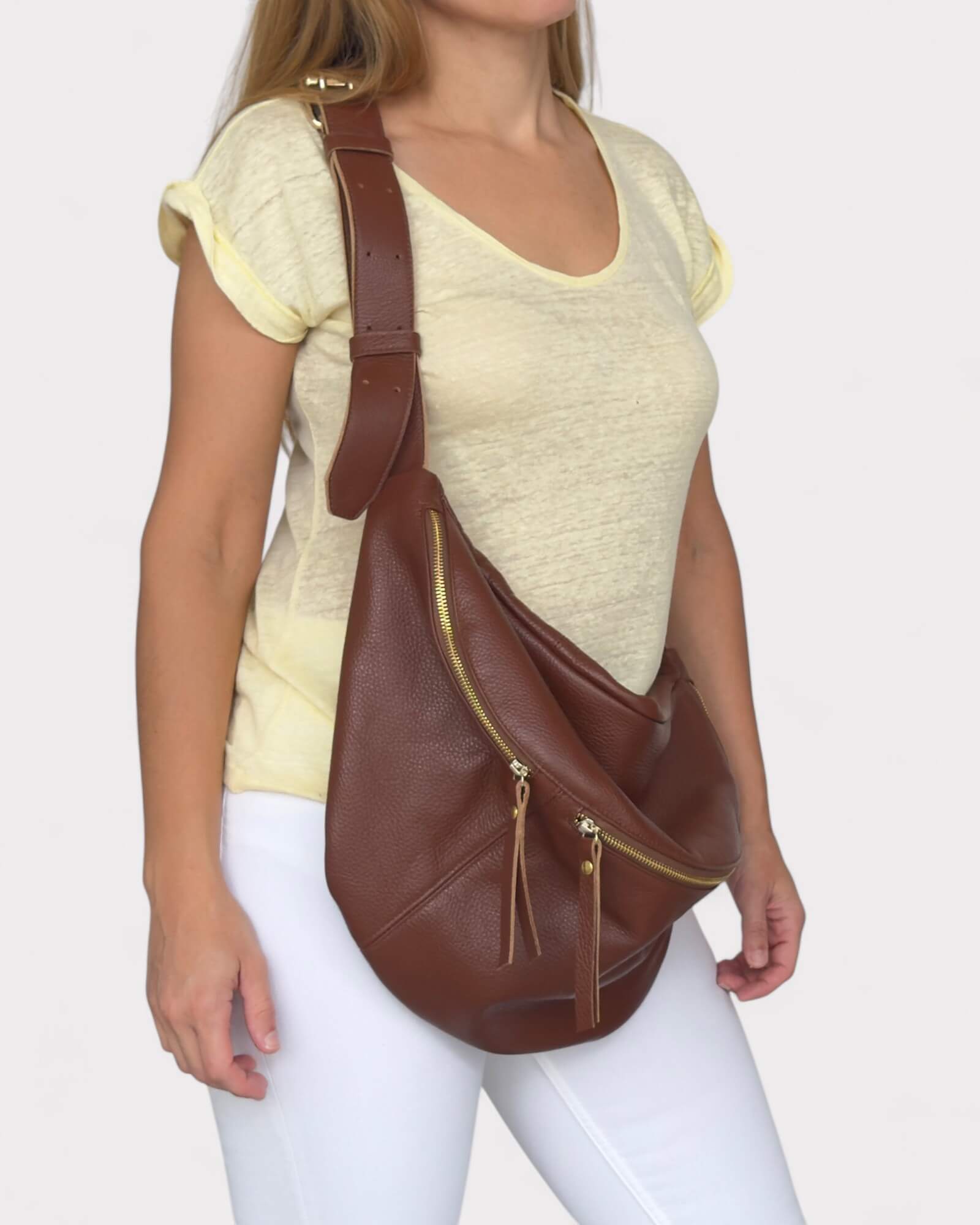 Woman carrying a brown sling bag on a plain background