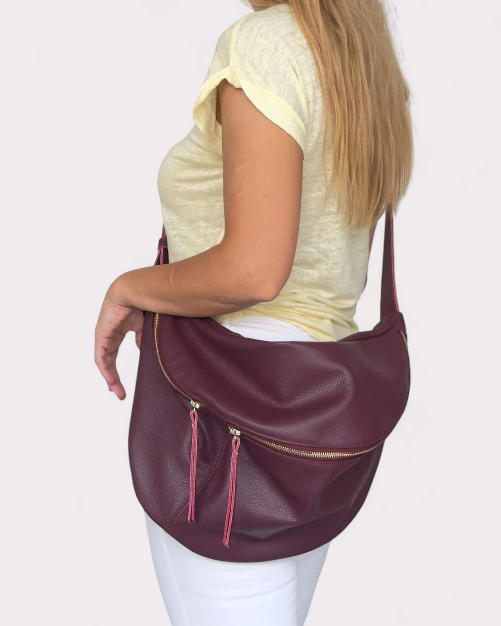 Model wearing a burgundy leather fanny pack on a plain background