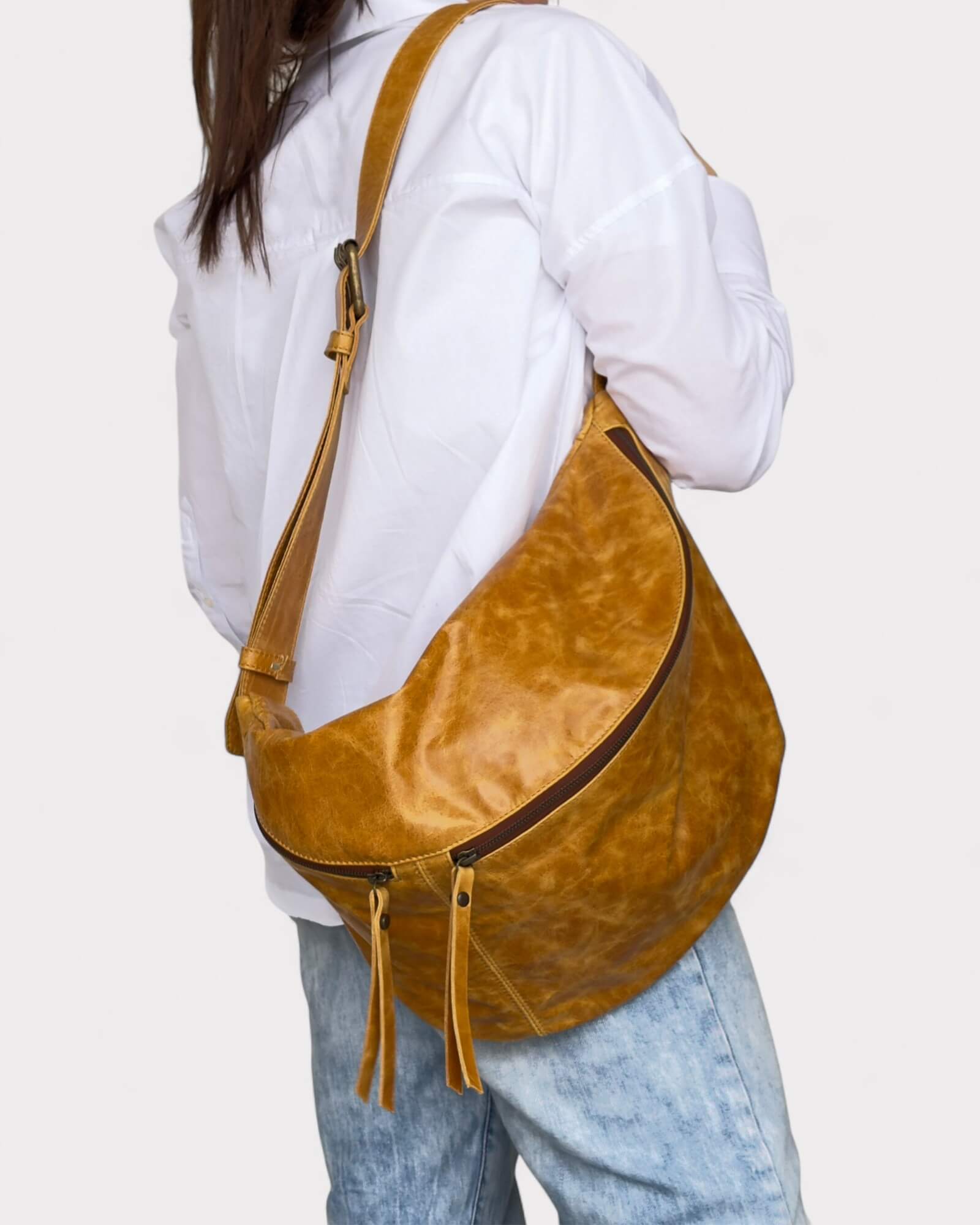 Person wearing a tan shoulder bag on a plain background