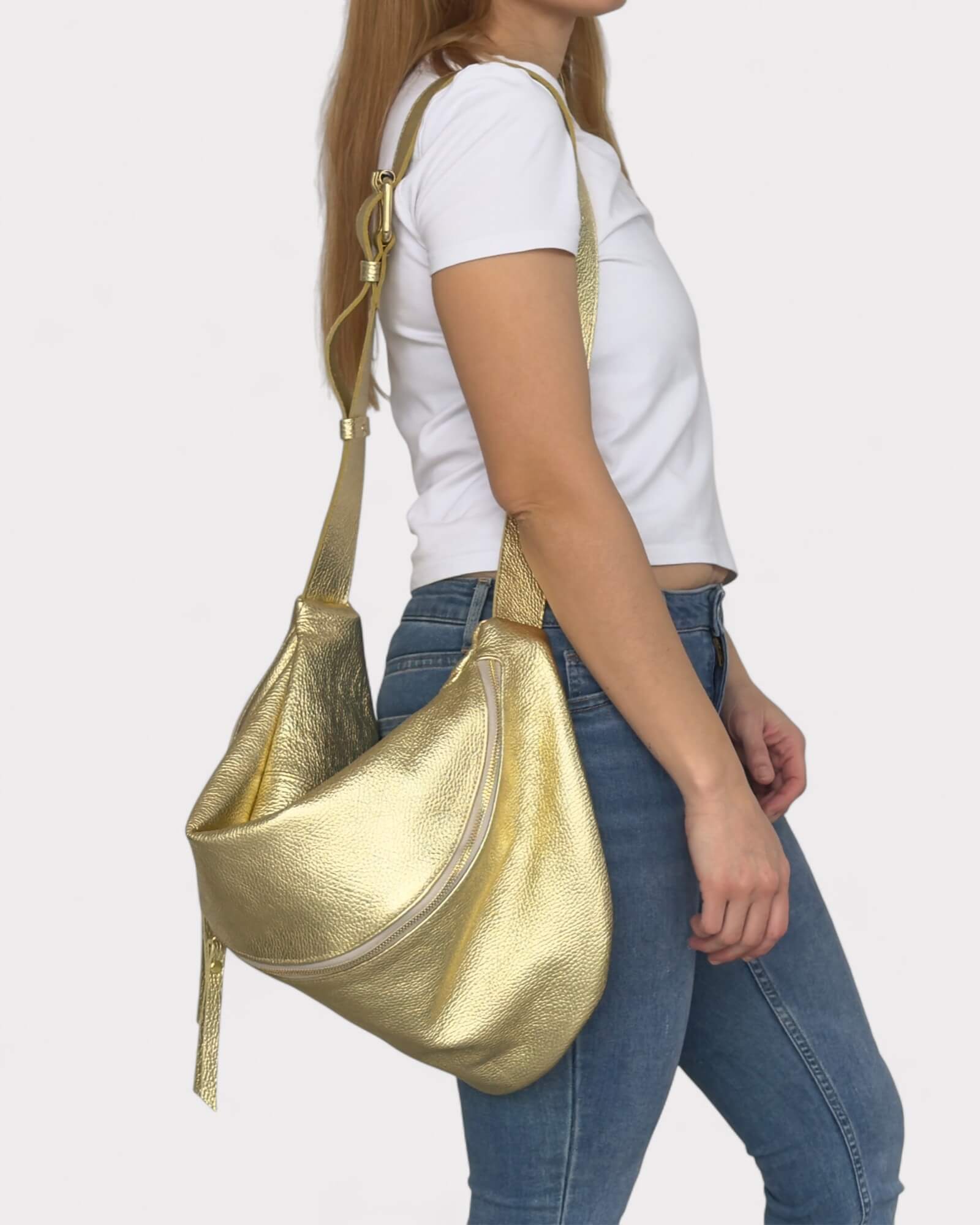 Woman wearing a gold handbag on a plain background