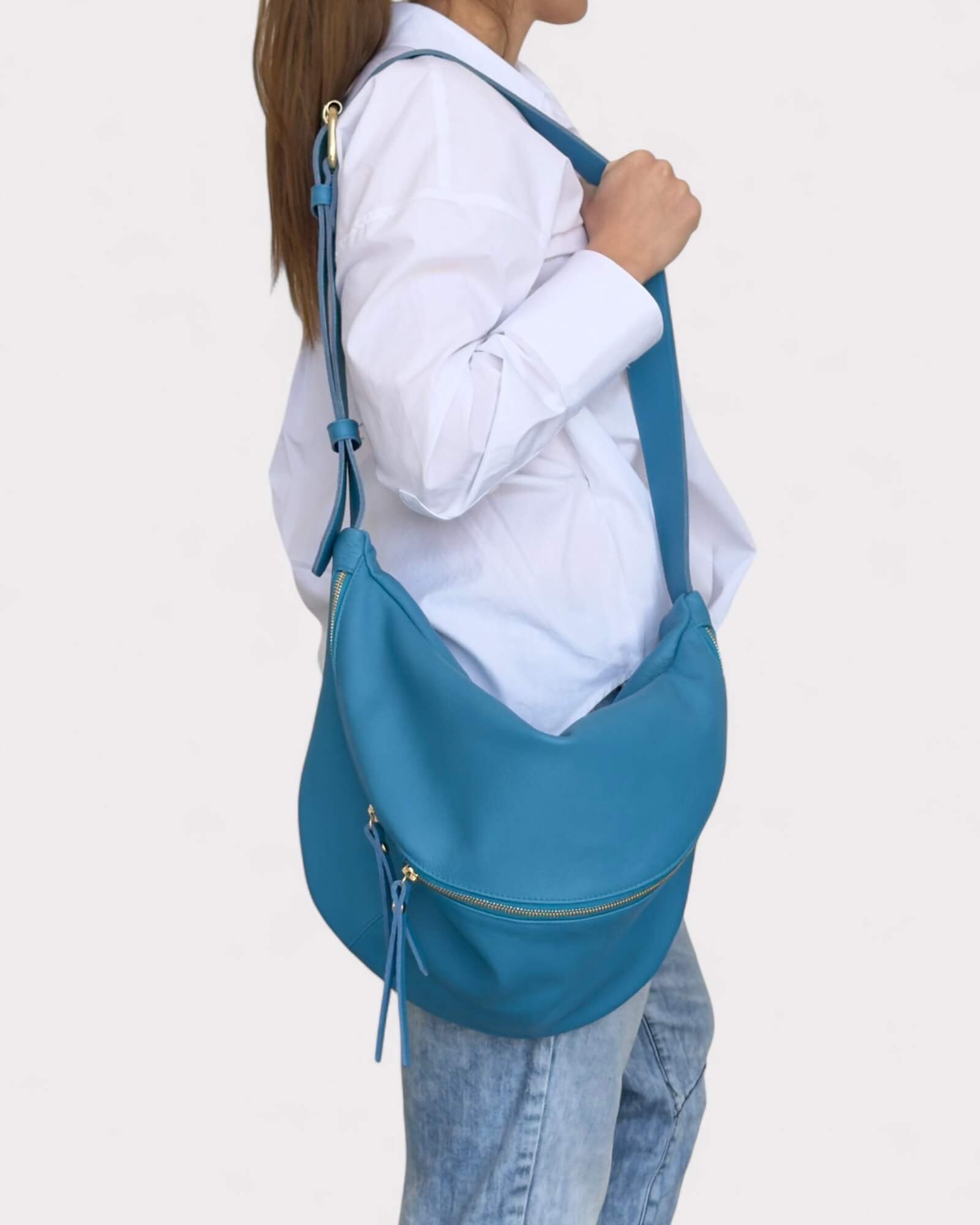 Person holding a blue handbag against a plain background