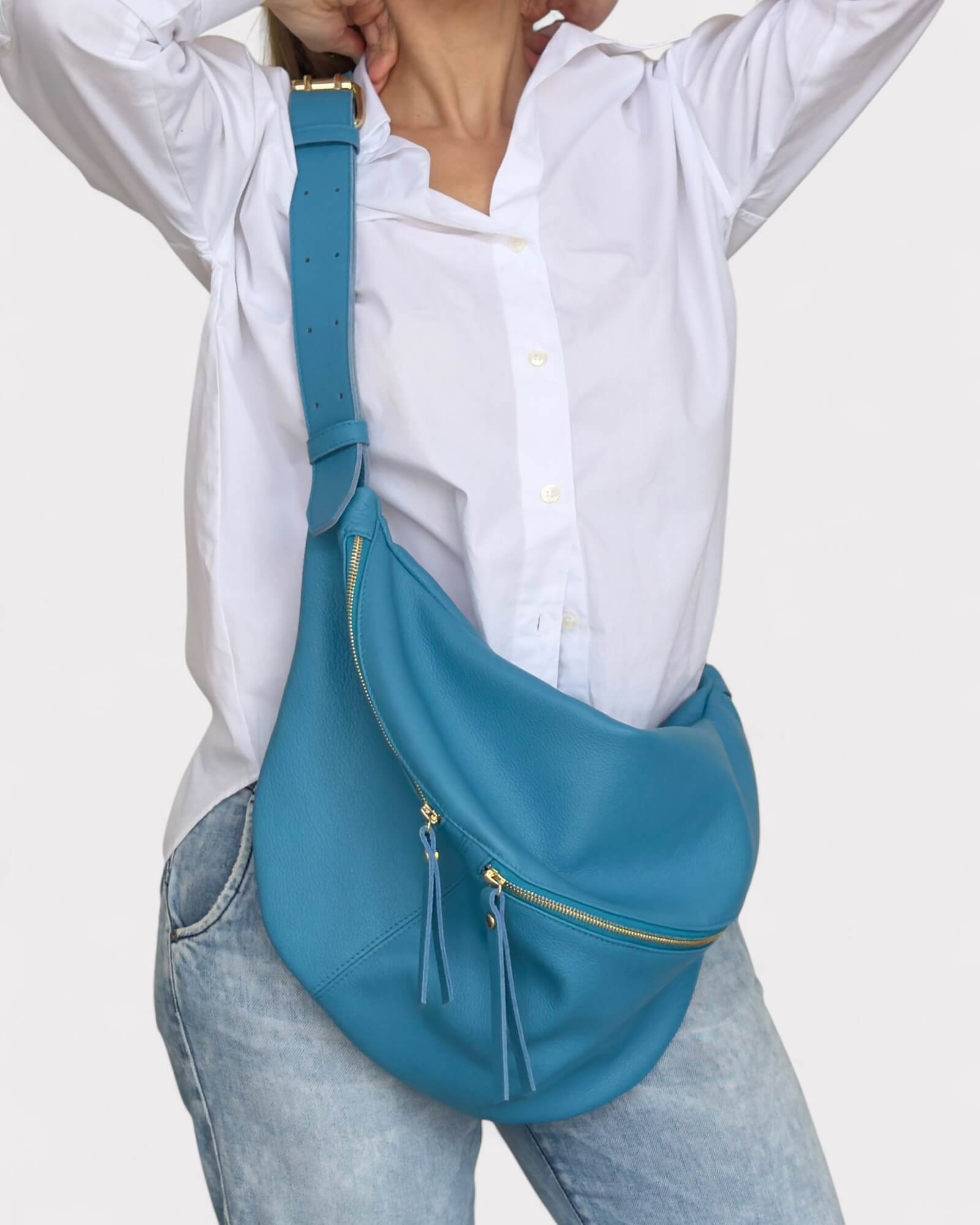 Person wearing a blue belt bag over one shoulder on a white background