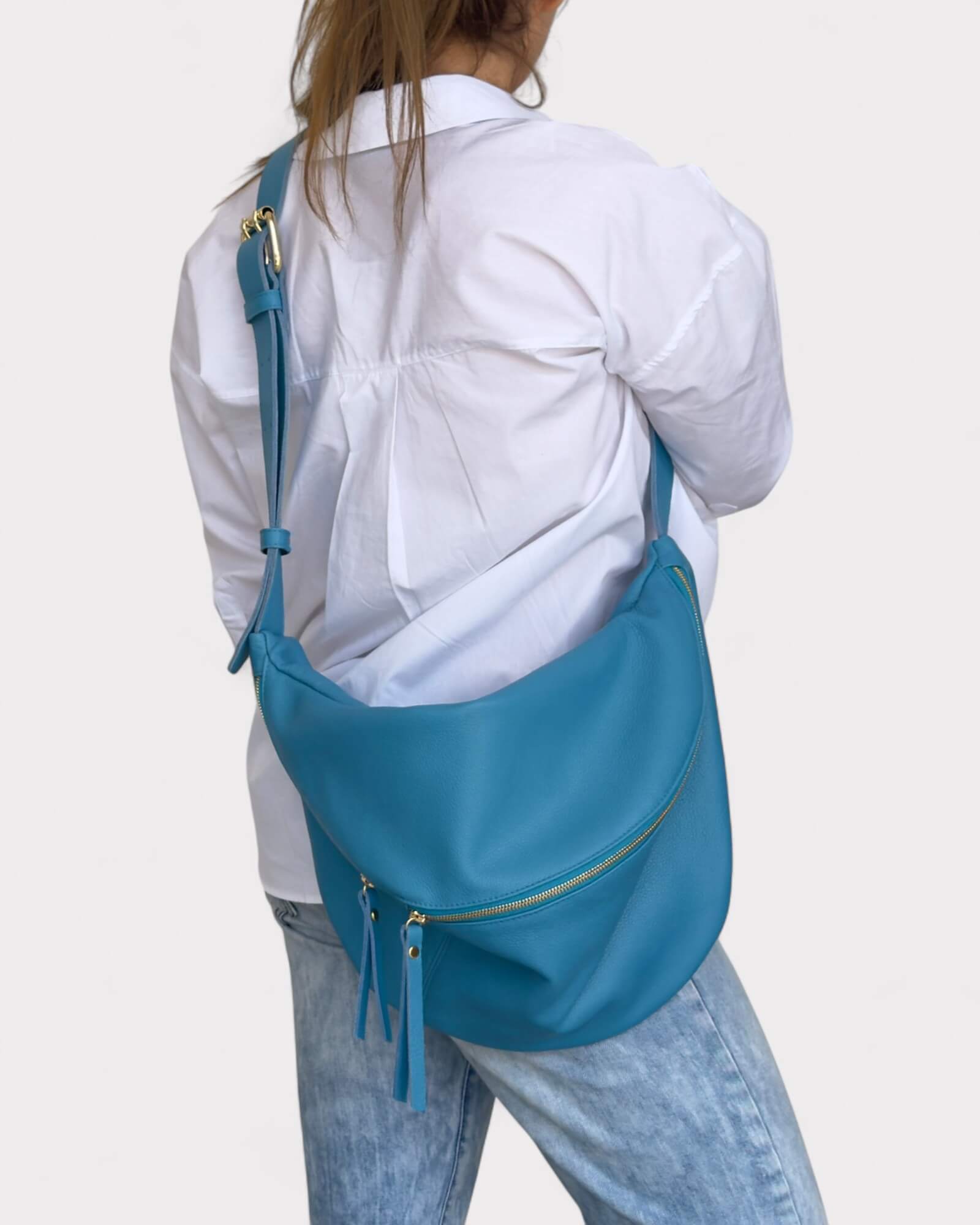 Person wearing a blue fanny pack bag over one shoulder on a white background