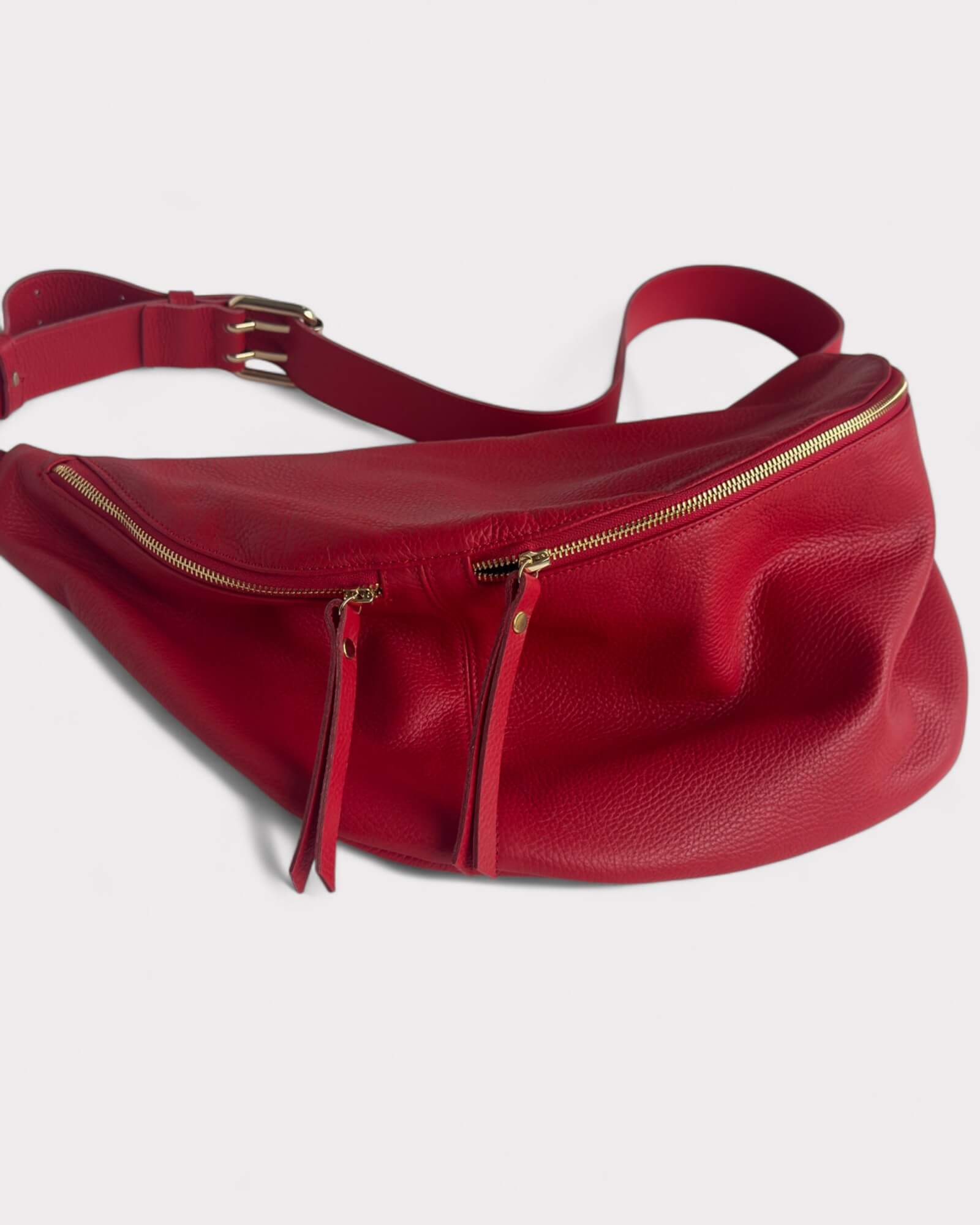 Red leather belt bag with gold zippers on a white background
