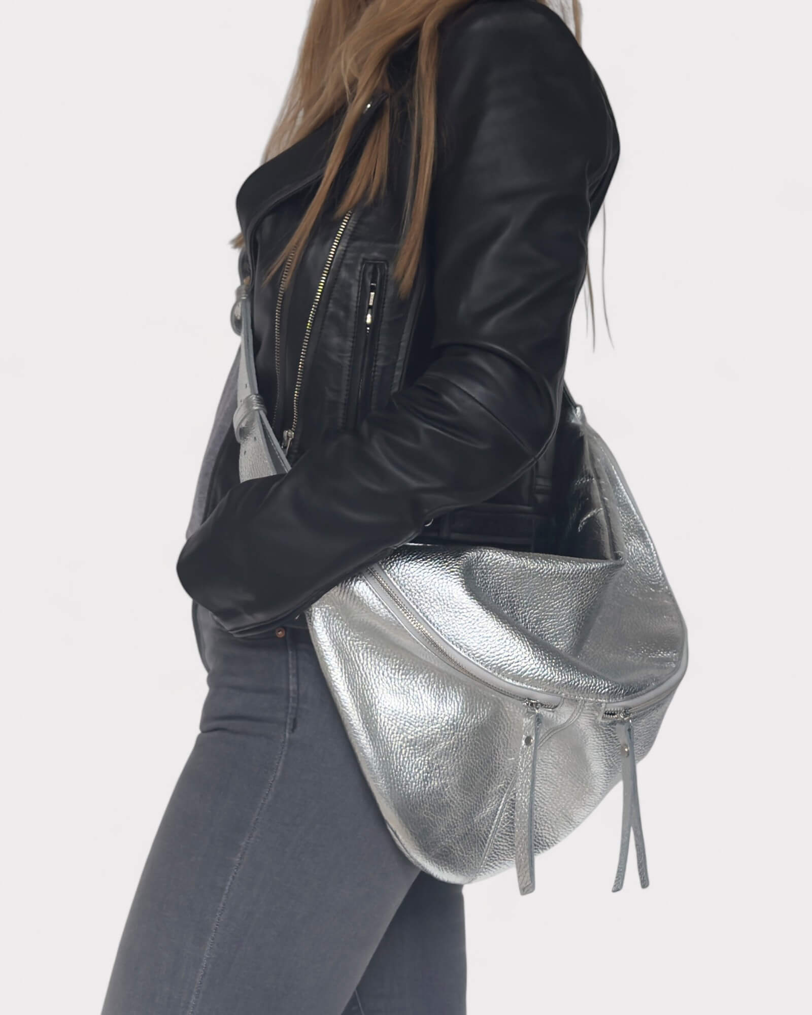Person wearing a silver sling bag on a white background