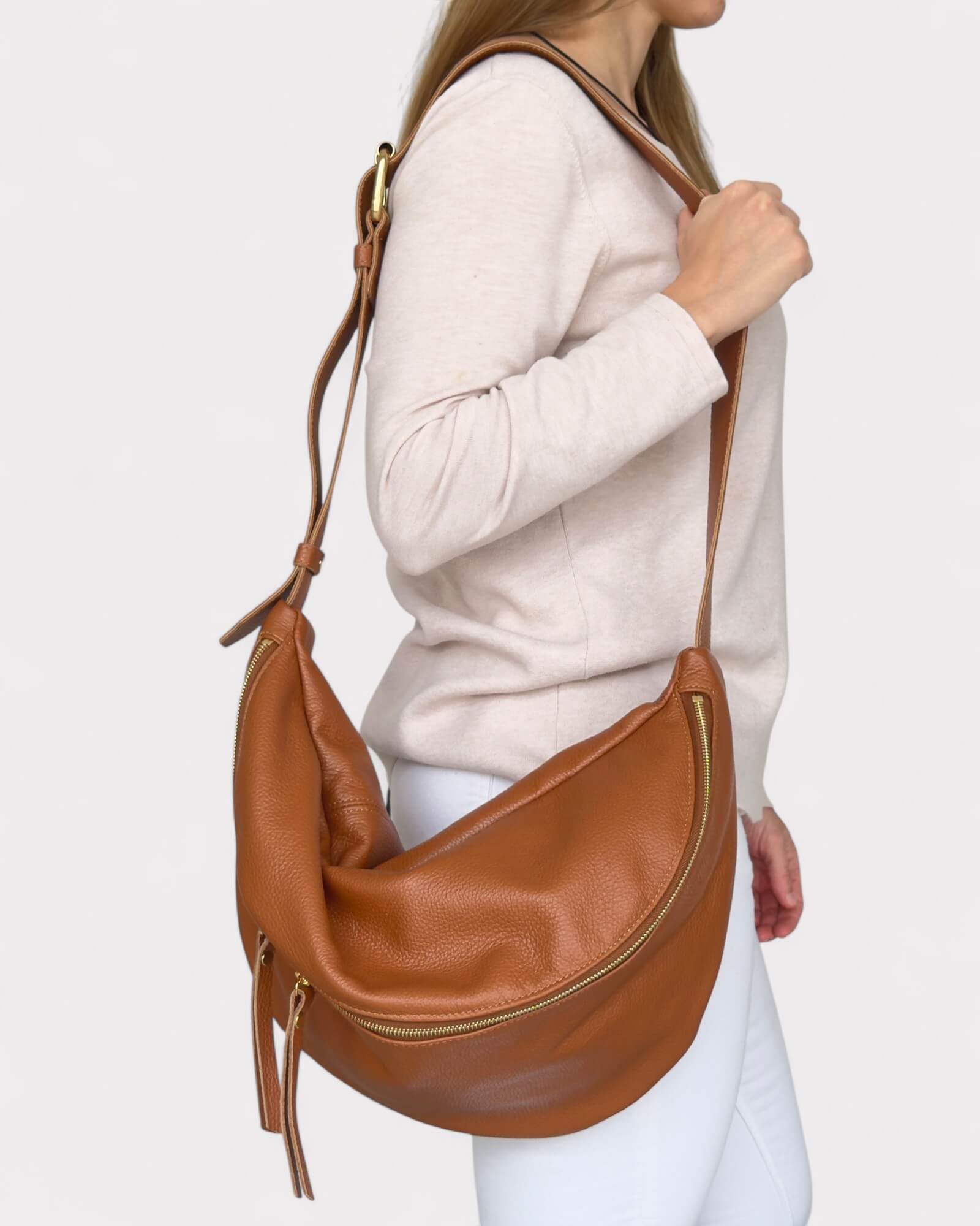 Tan leather chest bag worn by a person on a white background