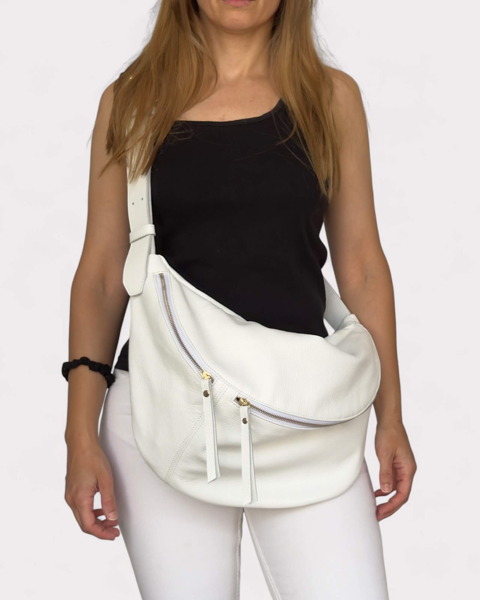 Woman wearing a white large fanny bag on a plain background