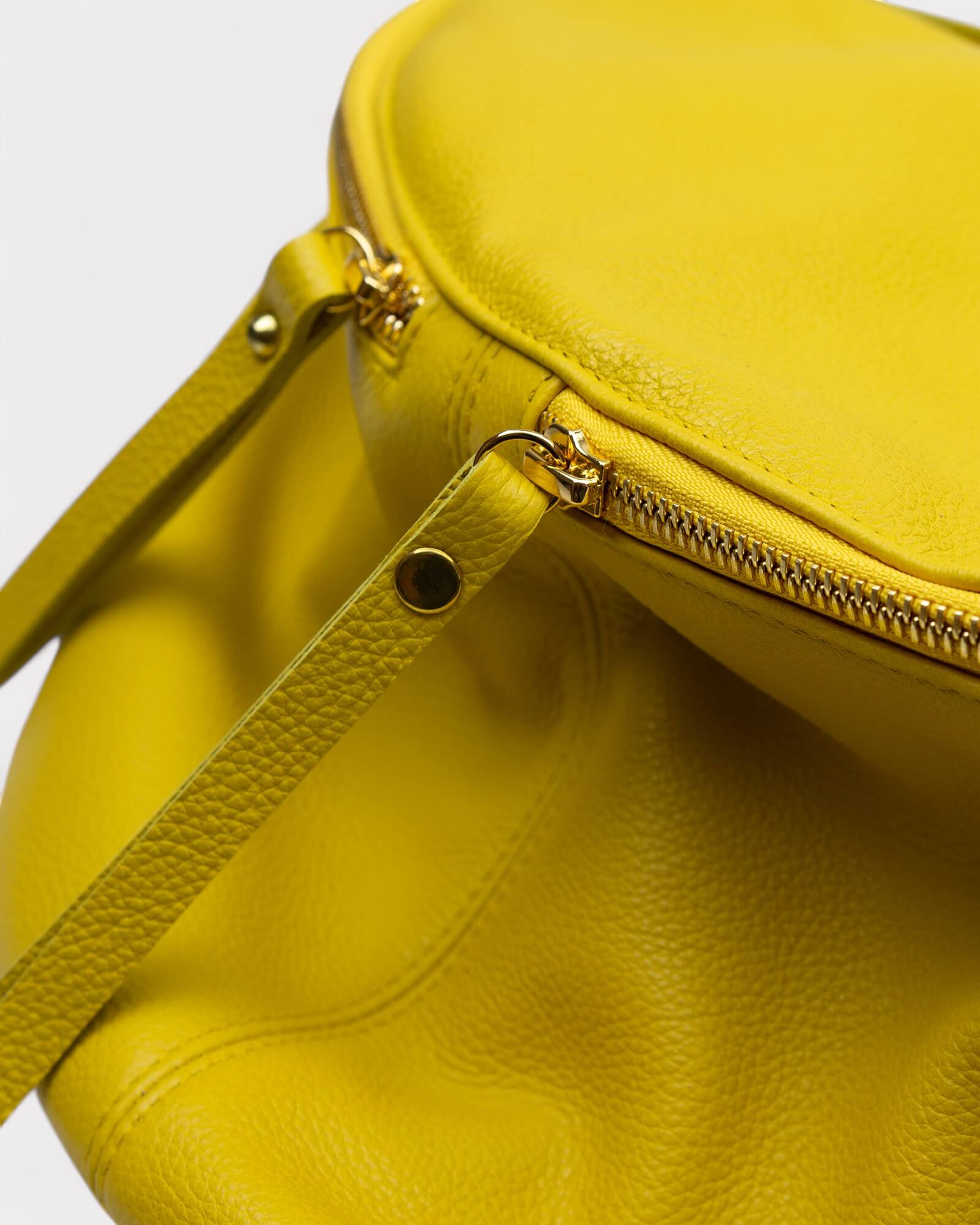 Yellow handbag with a gold zipper on a light gray background