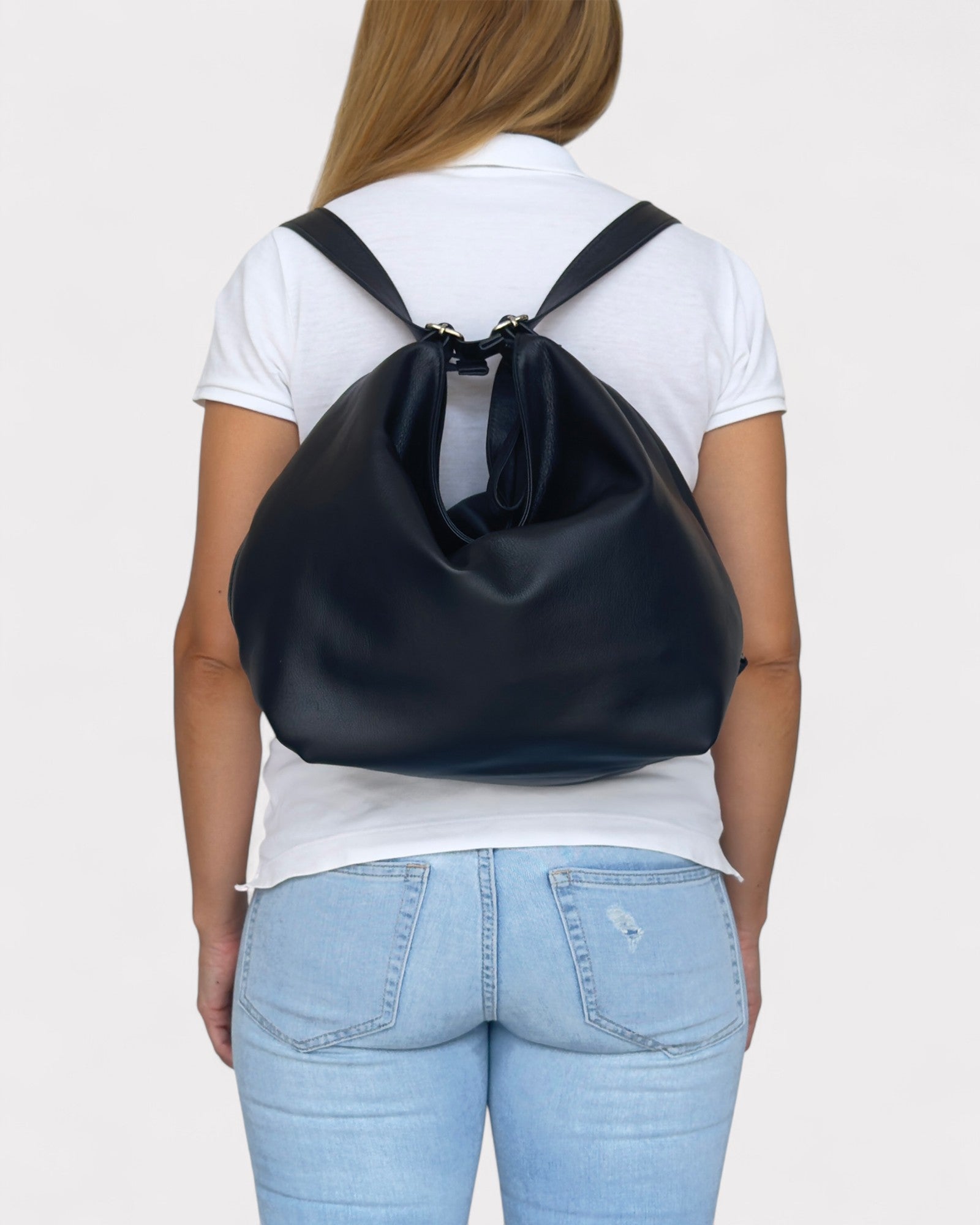 Person wearing a black convertible bag over their shoulder on a plain background