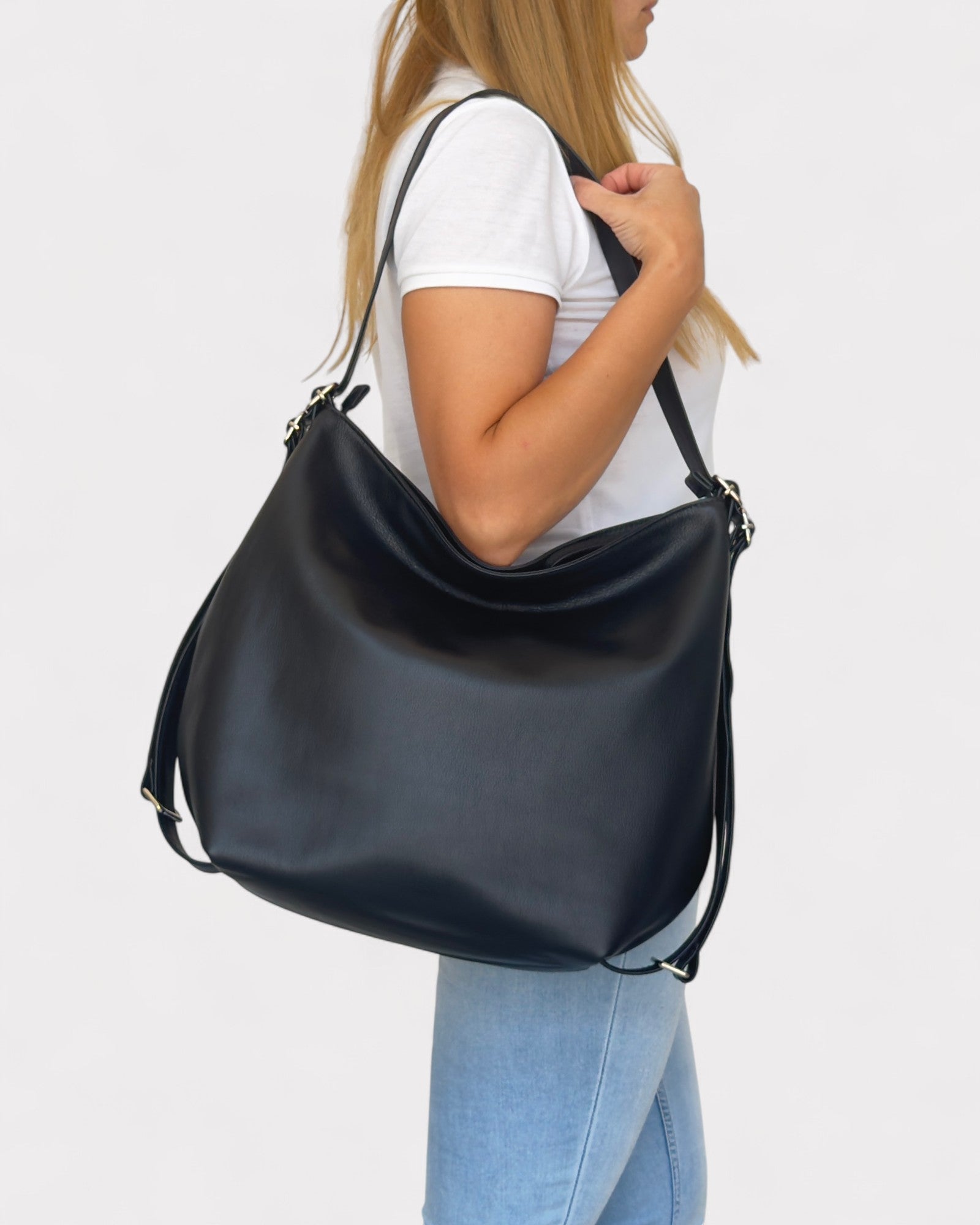 Person holding a black shoulder bag against a white background