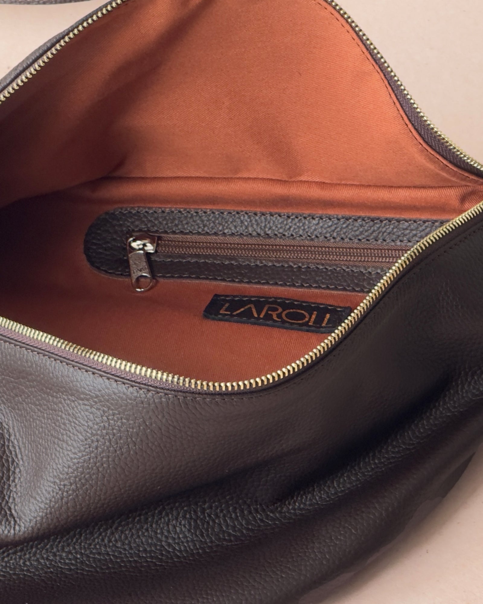 Close-up of a leather bag with a visible brand logo on a beige background