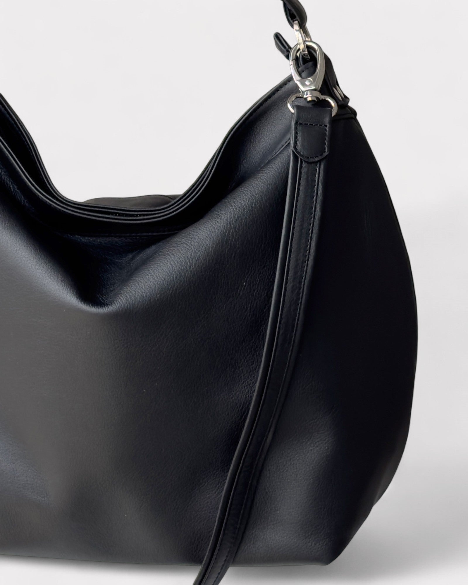 Black handbag with a strap on a light gray background