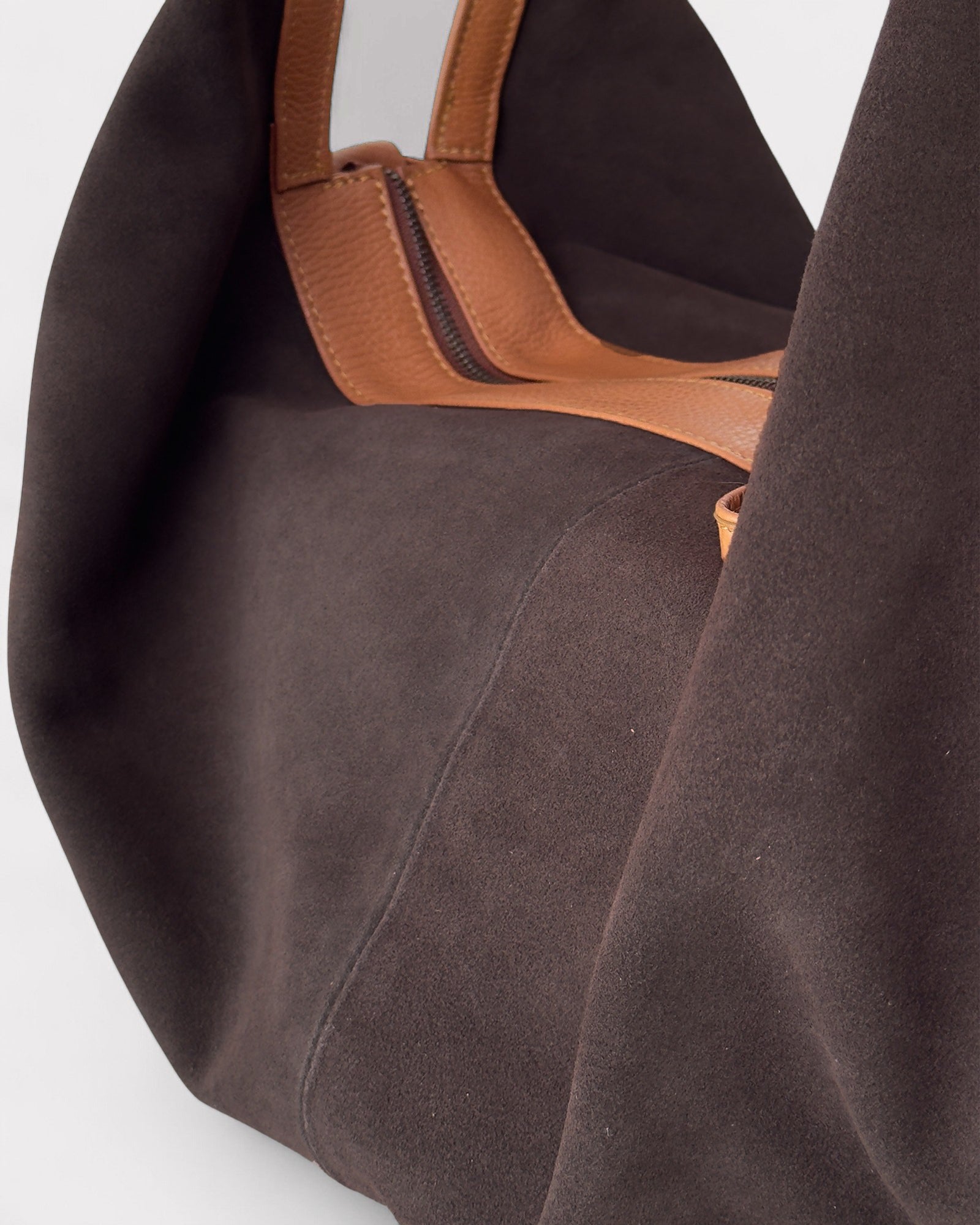 Brown suede handbag with a tan leather handle on a white background