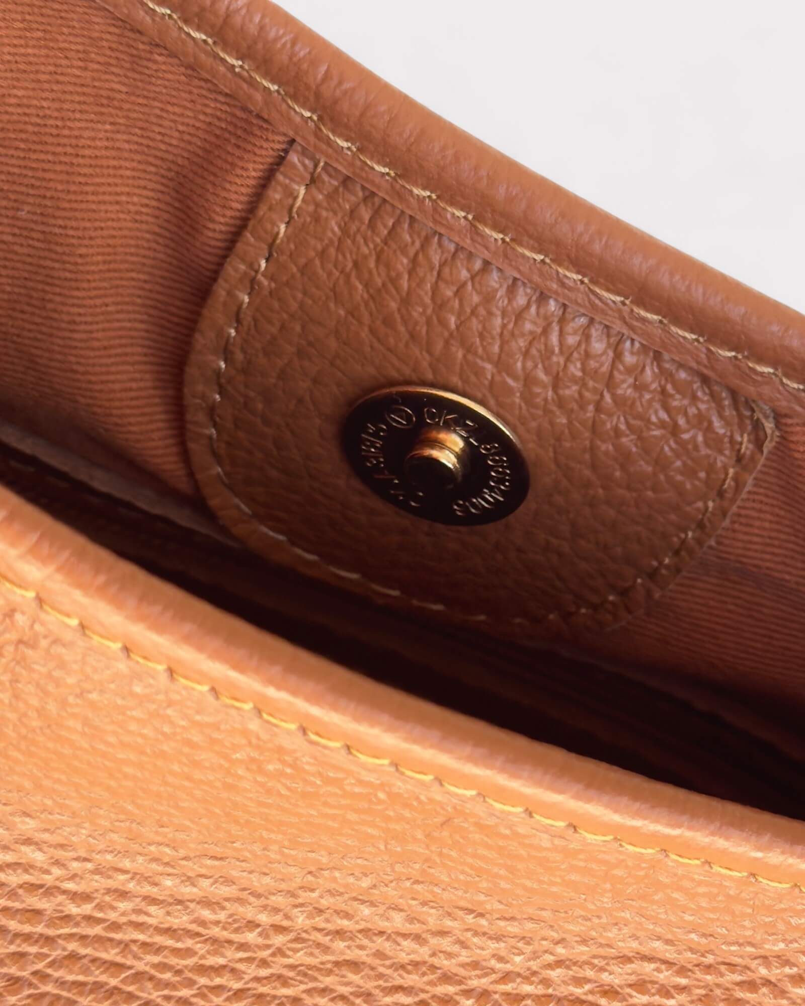 Close-up of a tan leather bag with a magnetic snap