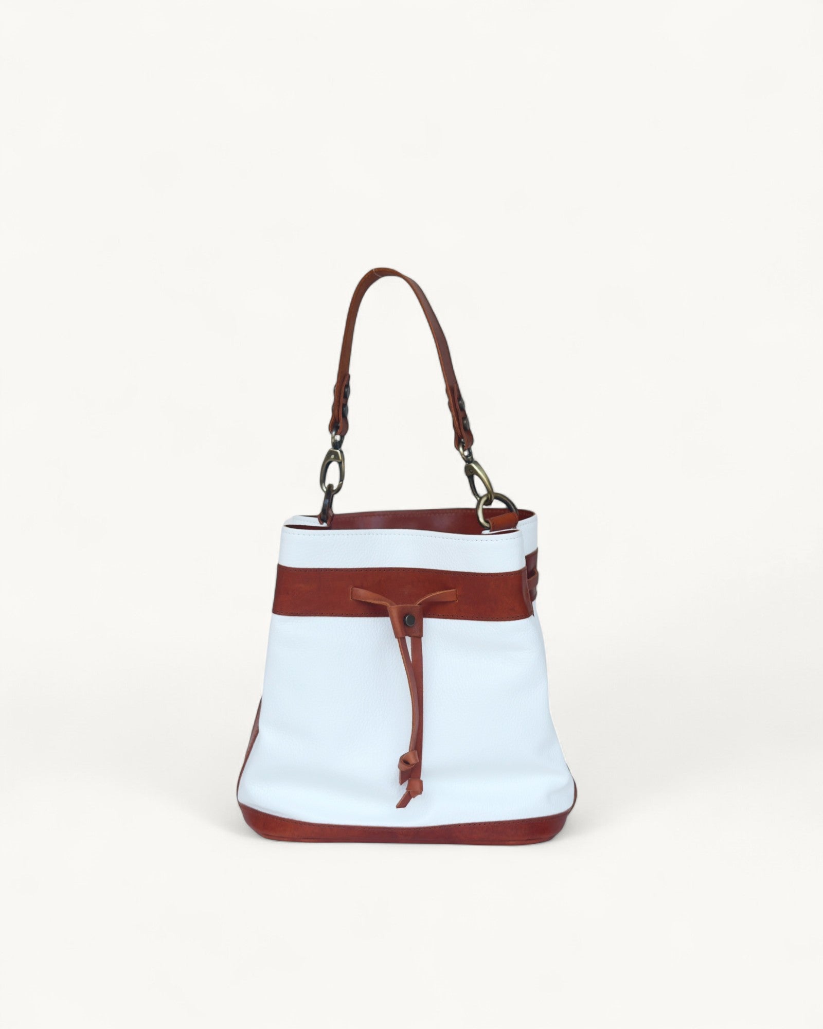 White bucket bag with brown leather accents on a white background