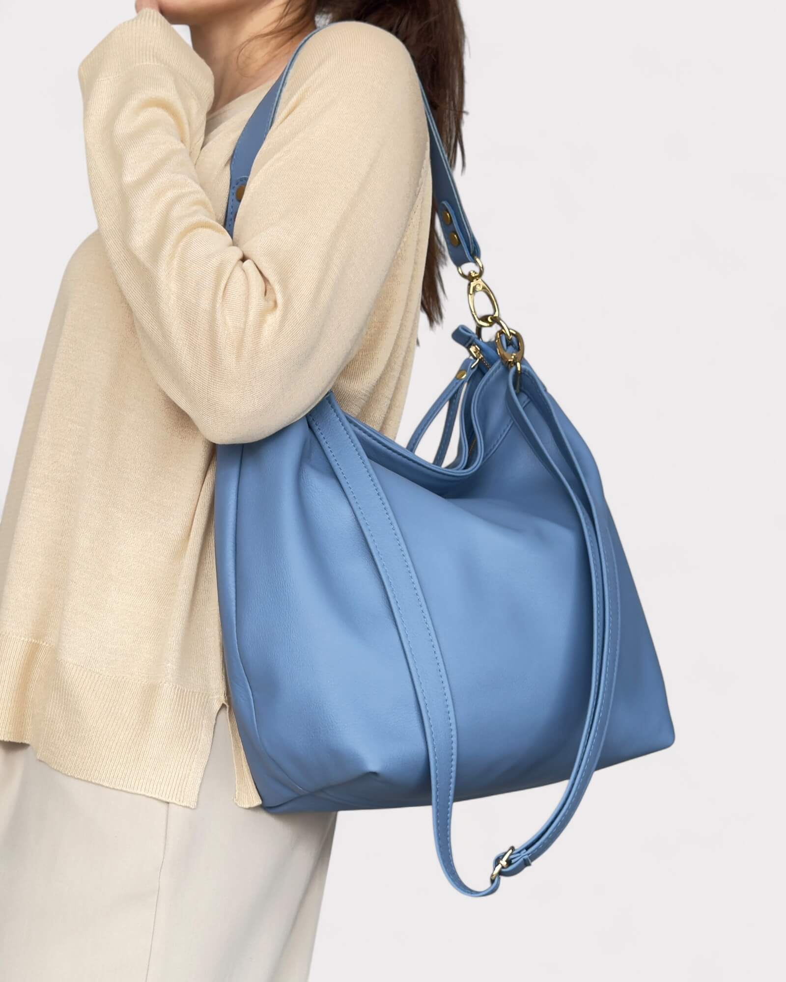 Person holding a blue handbag against a plain background