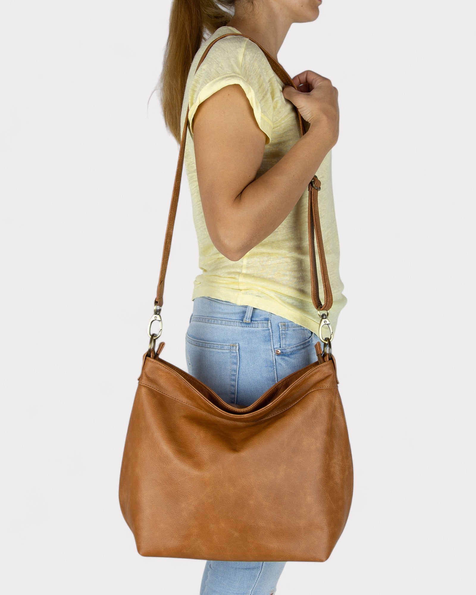 Woman holding a Tan distressed handbag against a plain background