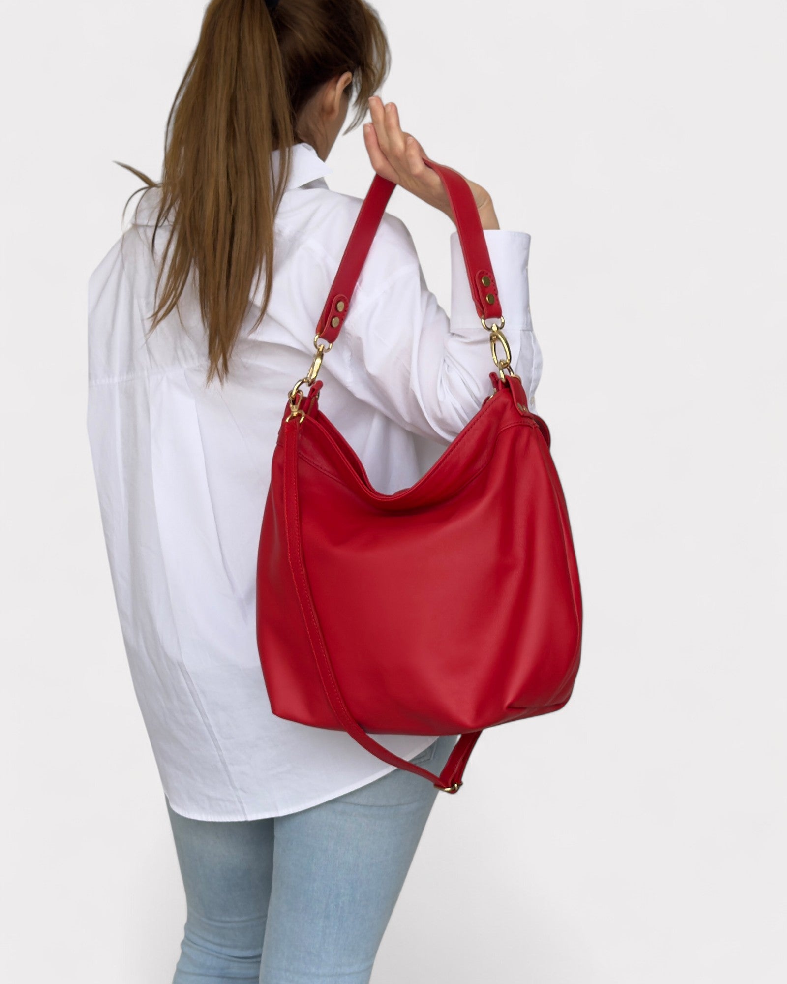 Person holding a red handbag against a white background