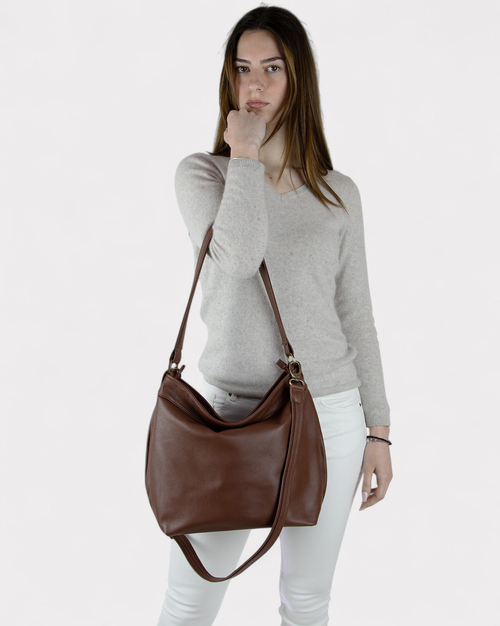 Woman holding a brown leather handbag against a white background