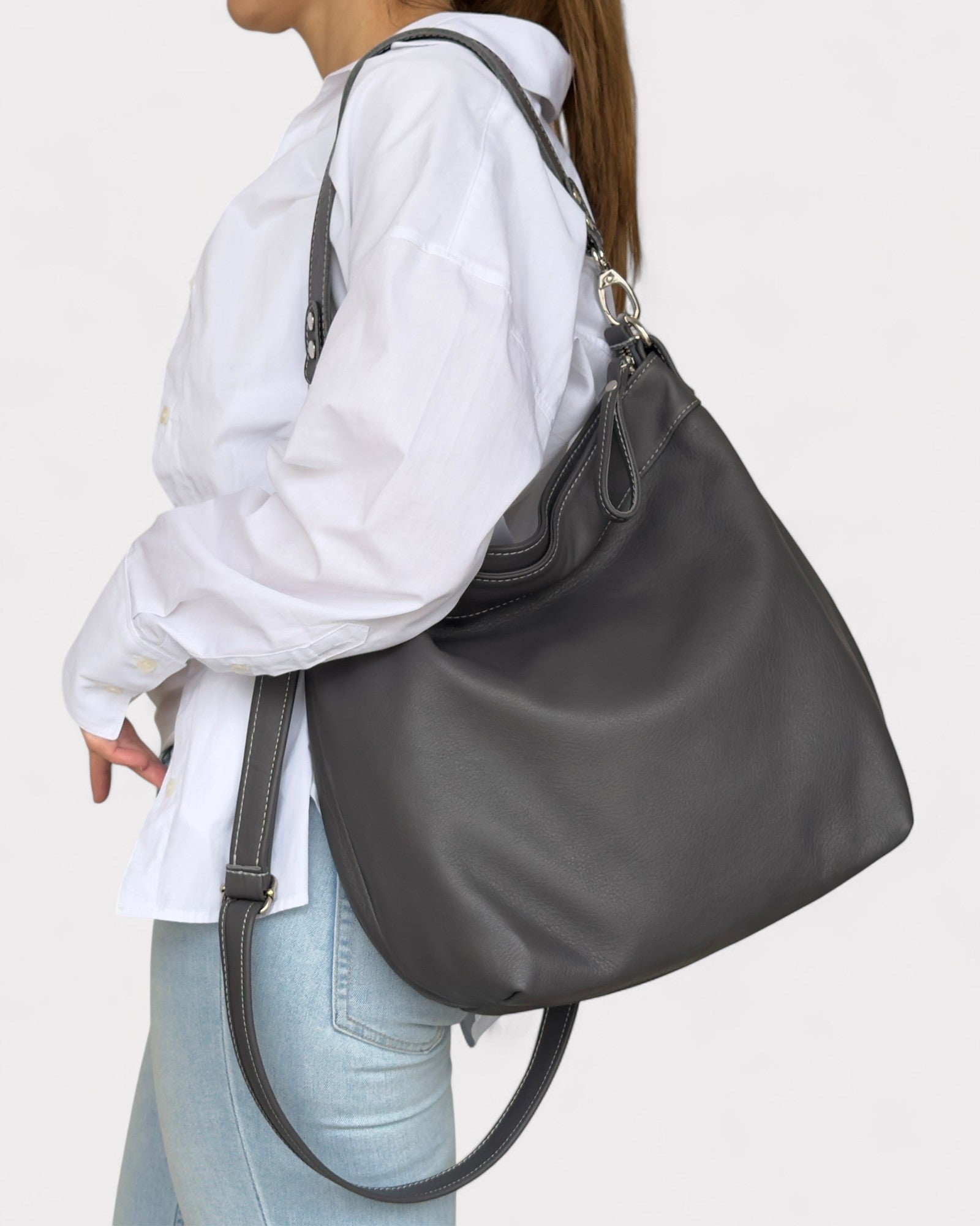 Person wearing a gray shoulder bag on a plain background