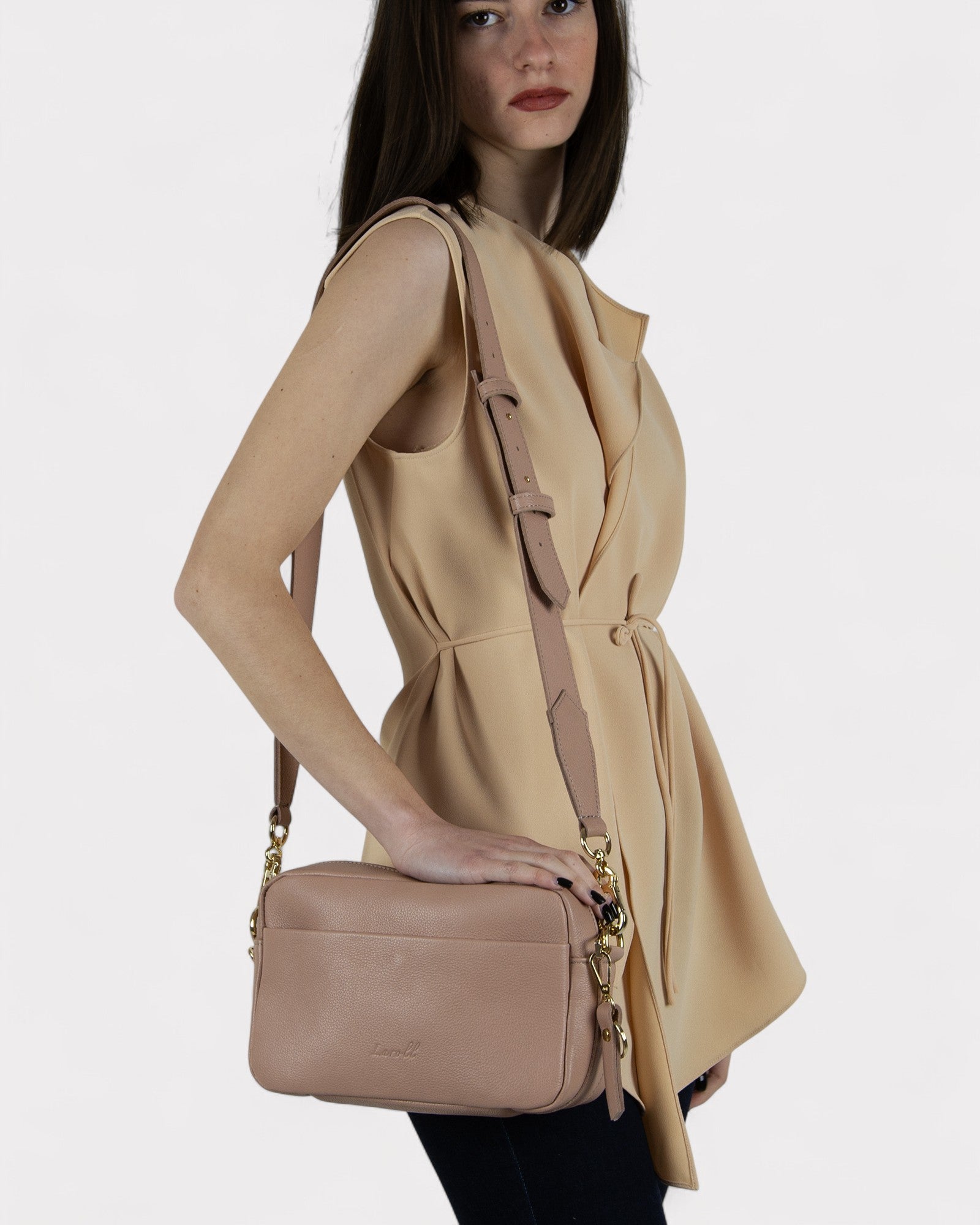 Woman holding a dusty rose handbag against a white background