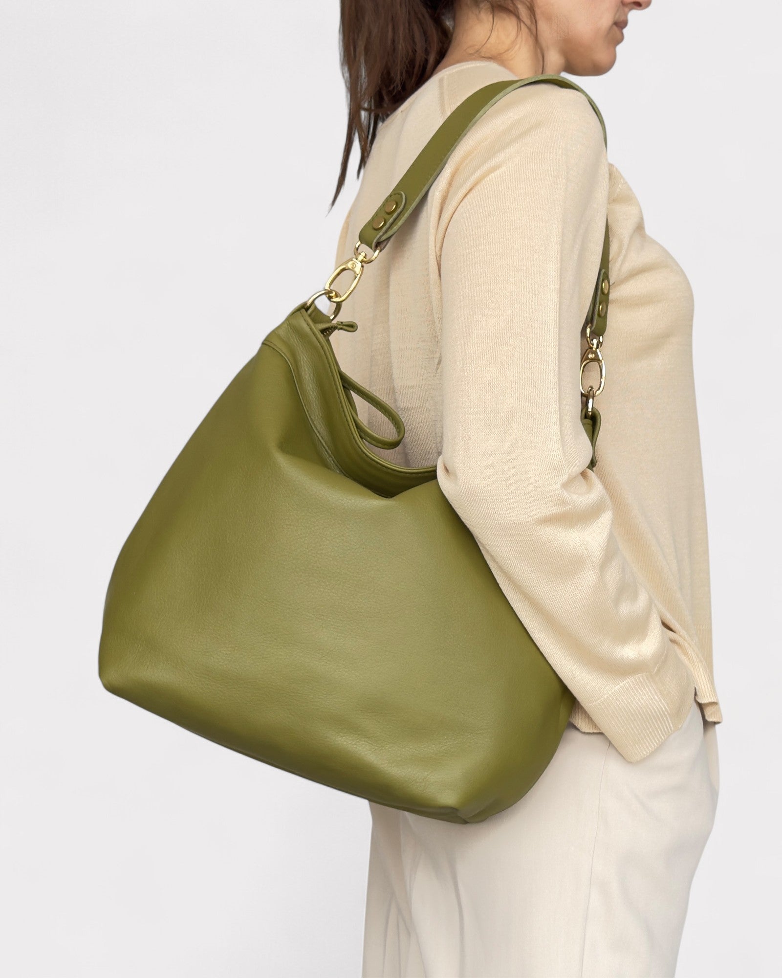 Person wearing a green handbag on a plain background