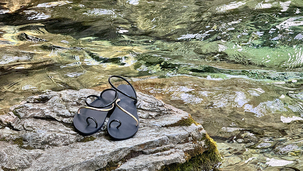 Black sandals on a rock by a stream