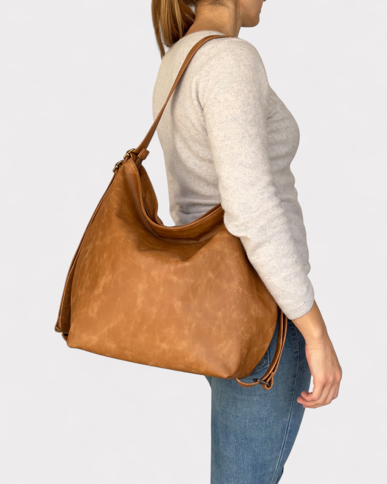 Person wearing a tan leather handbag on a plain background