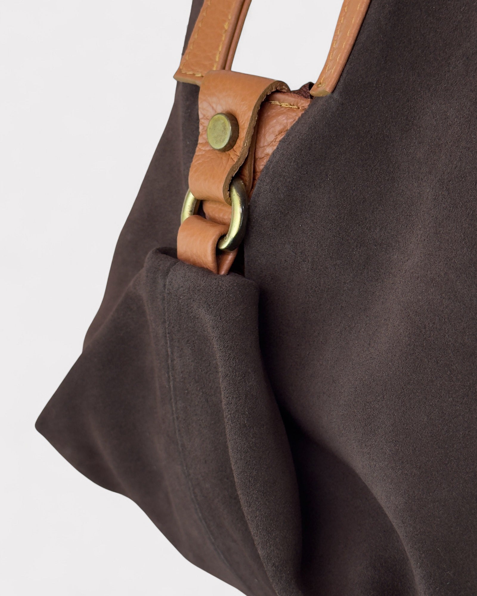 Brown handbag with leather handle and strap on a light gray background