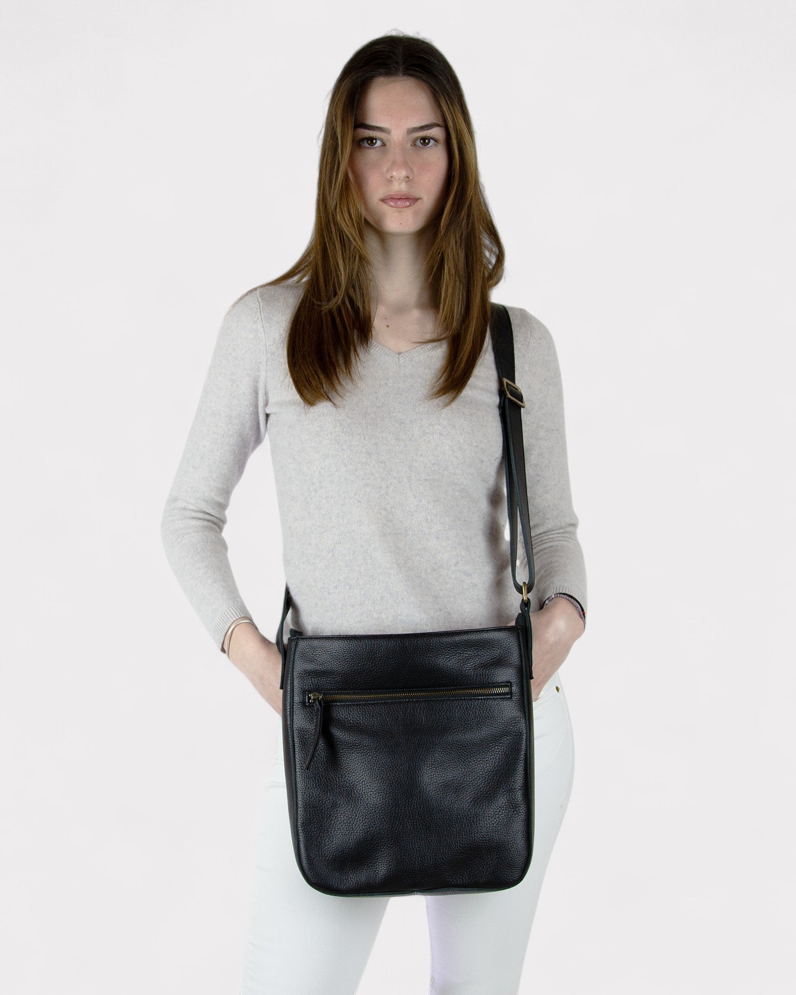 Woman holding a black leather crossbody bag against a white background