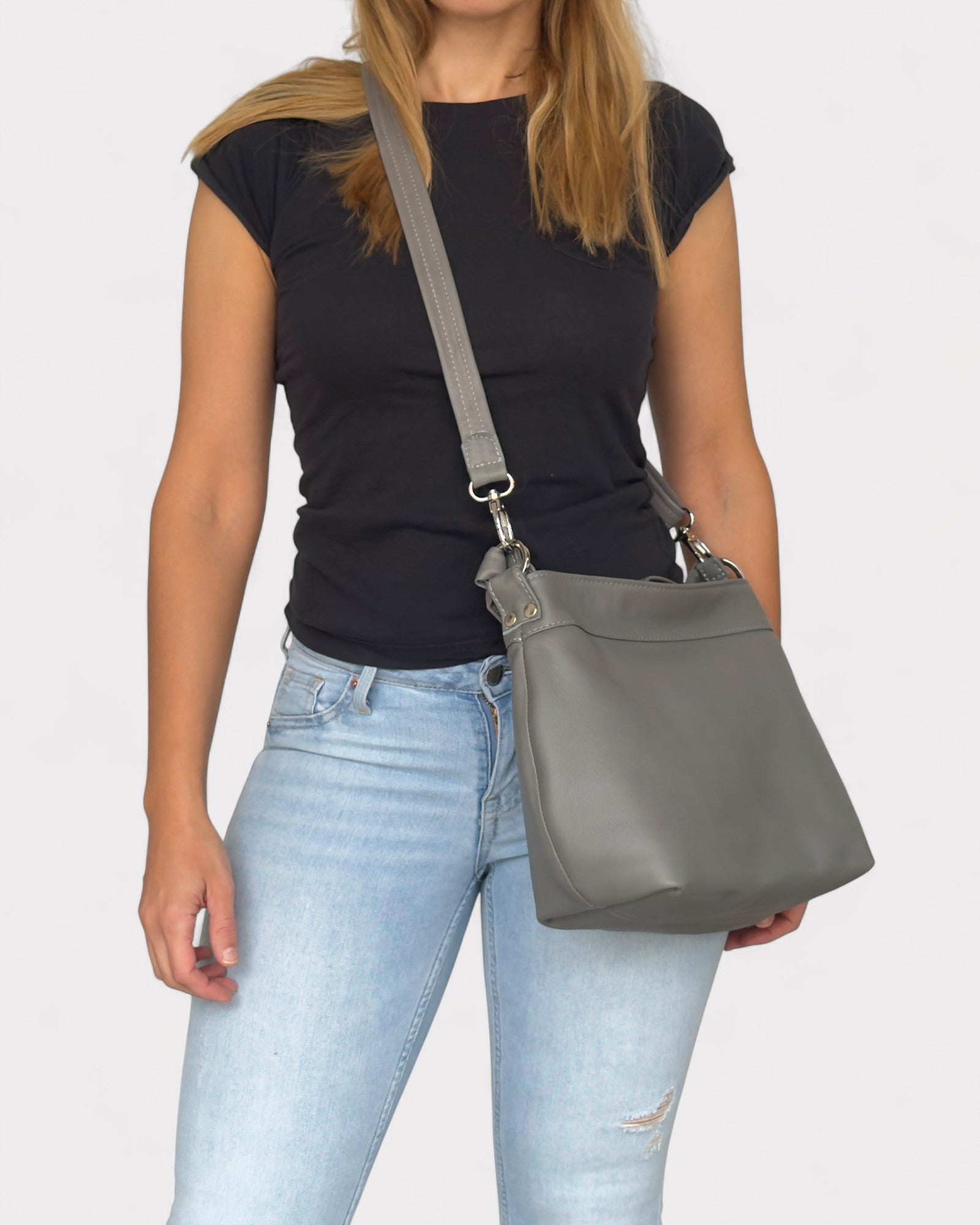 Woman holding a gray shoulder bag against a plain background