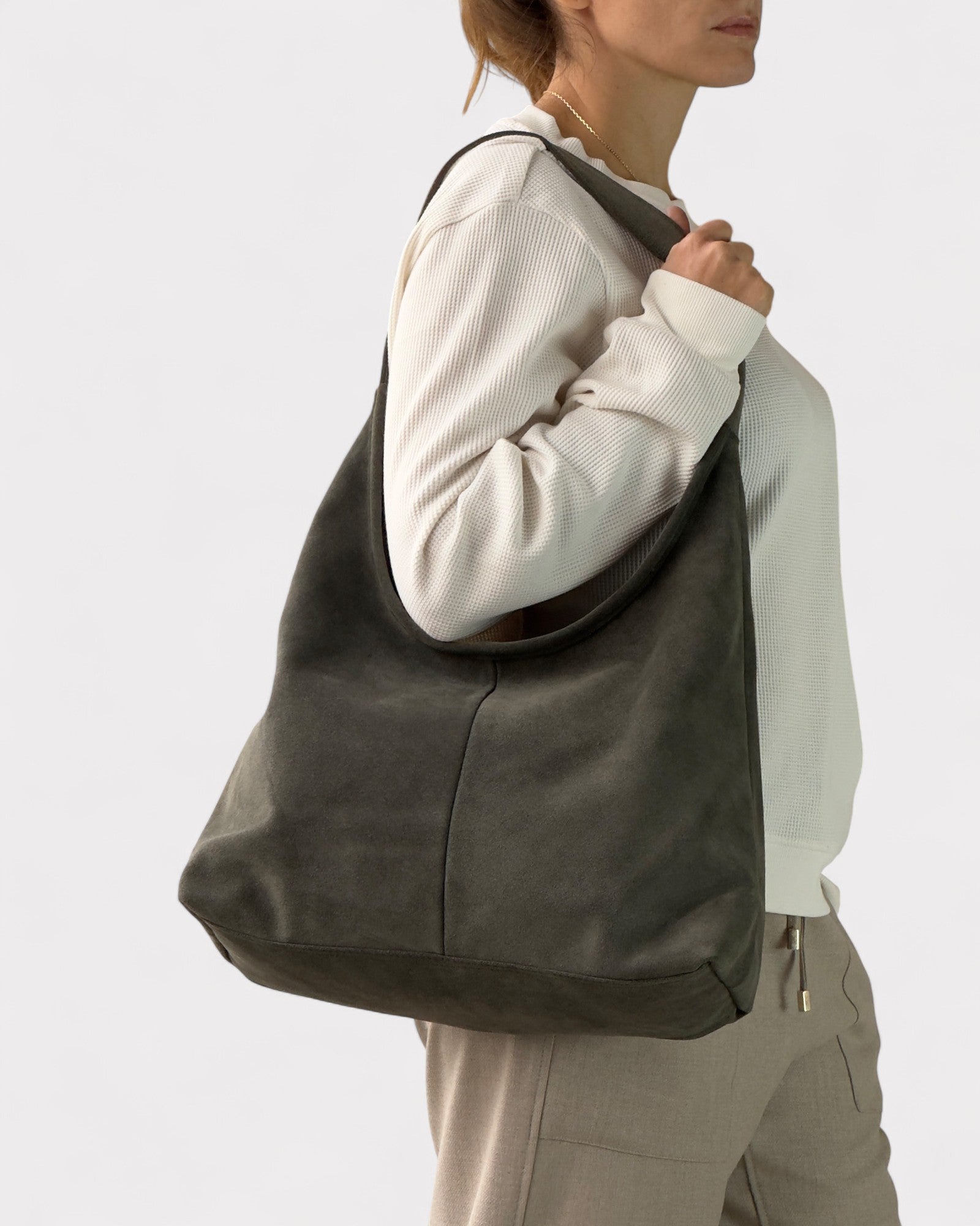 Person wearing a large dark green bag on a light gray background
