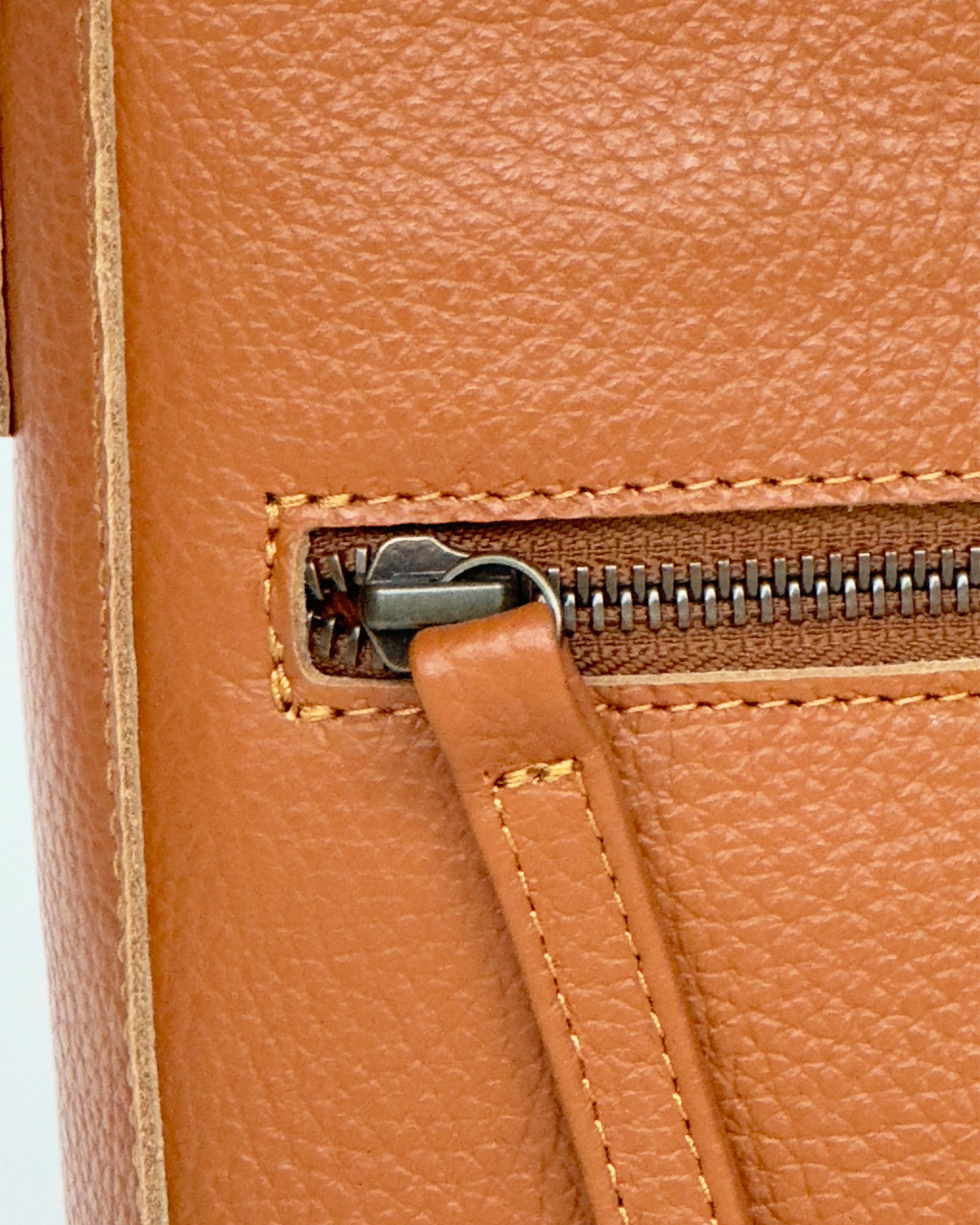 Close-up of a tan leather bag with a zipper