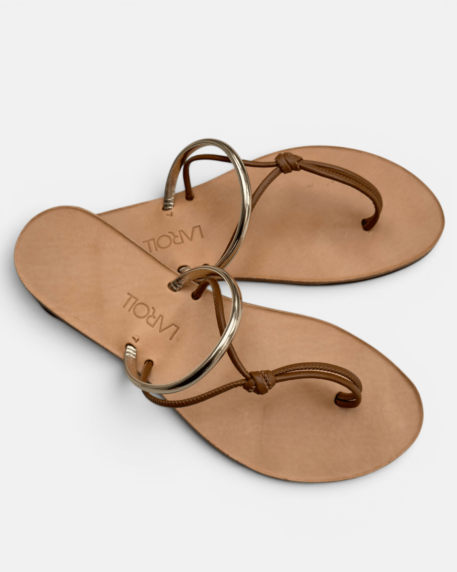 Pair of tan sandals with brown straps on a white background