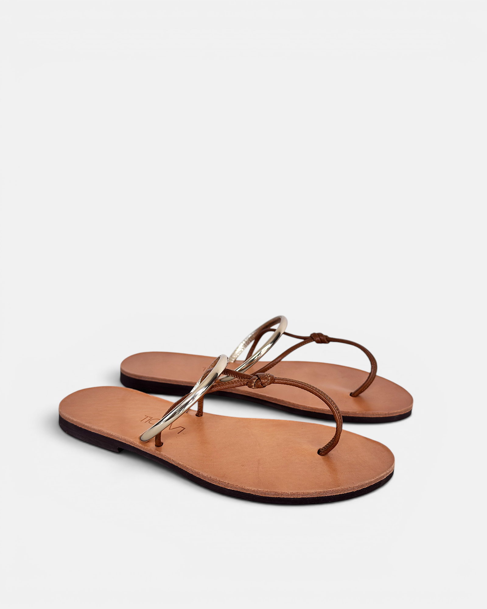 Pair of brown sandals with thin straps on a light gray background