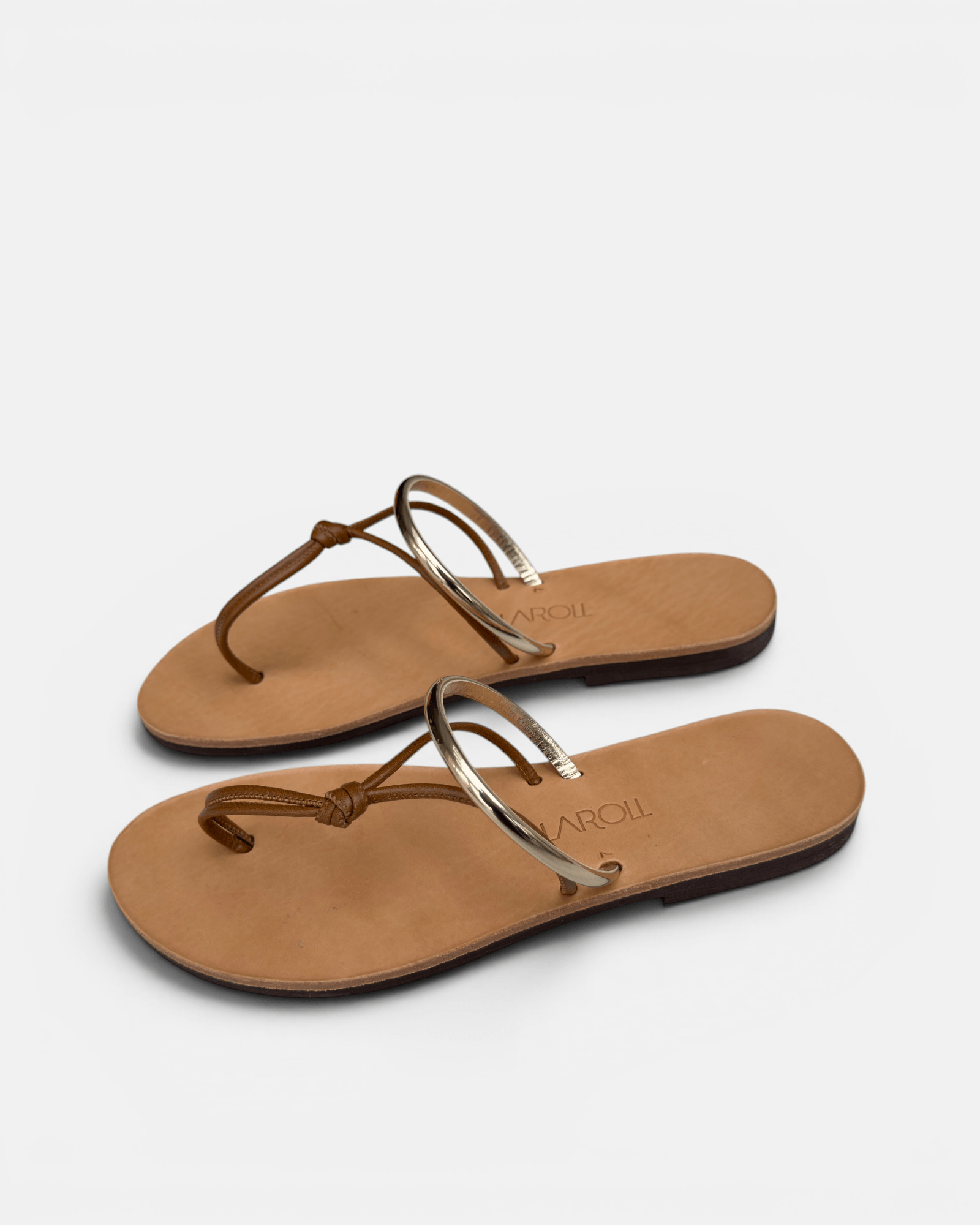 Pair of tan sandals with thin straps on a light gray background