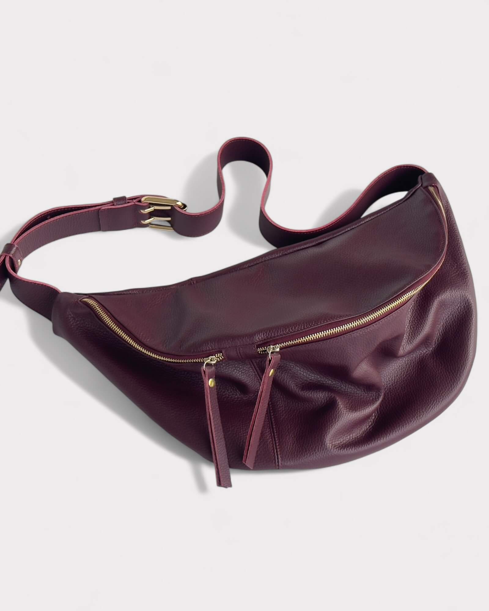 Burgundy leather waist bag on a light gray background