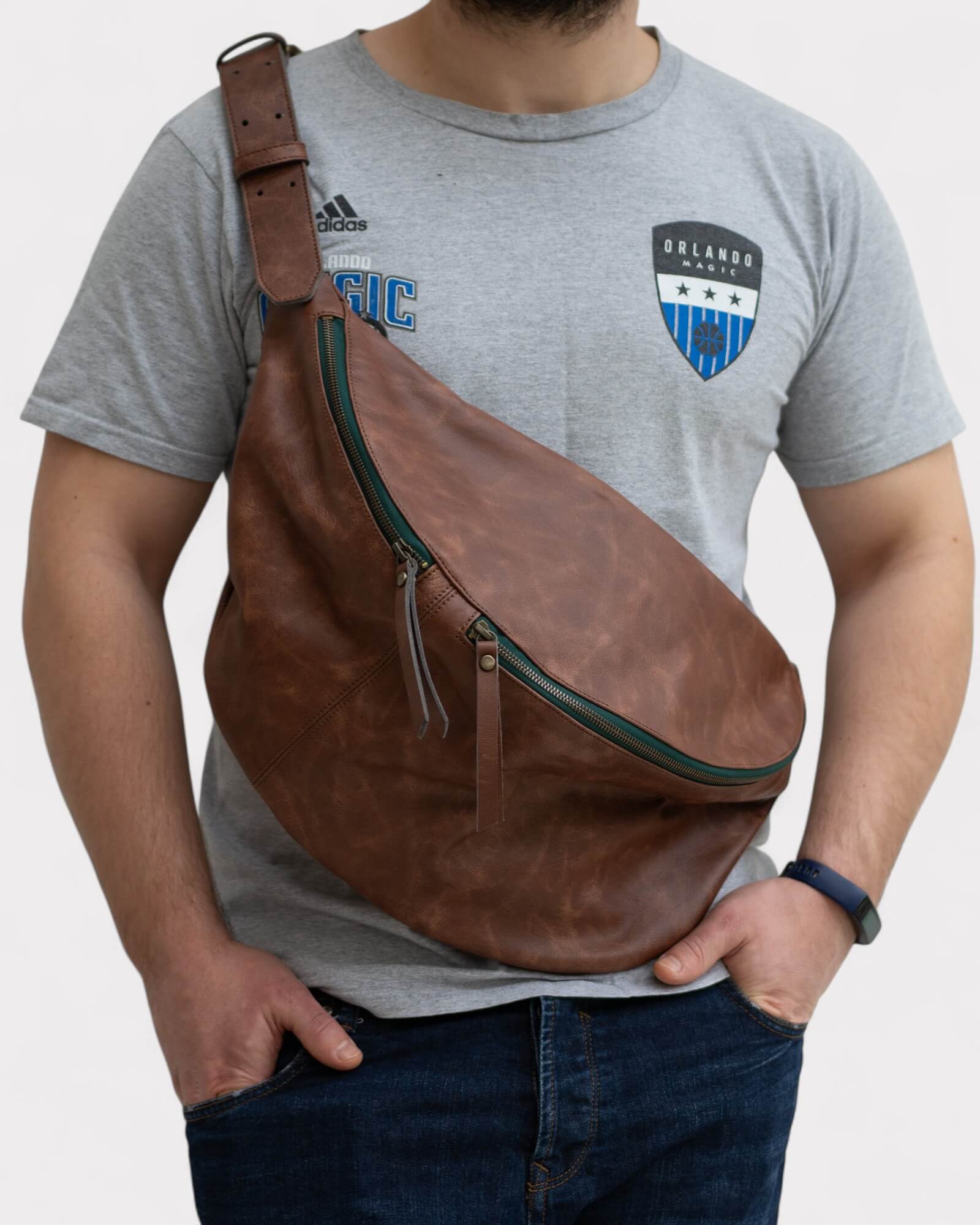 Person wearing a brown leather sling bag over one shoulder.