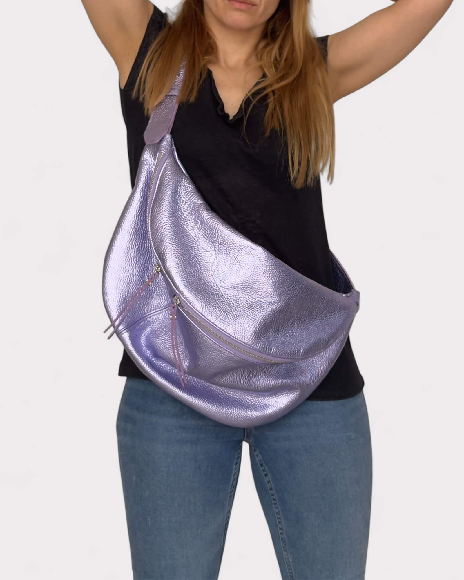 Person wearing a metallic lilac sling bag on a plain background