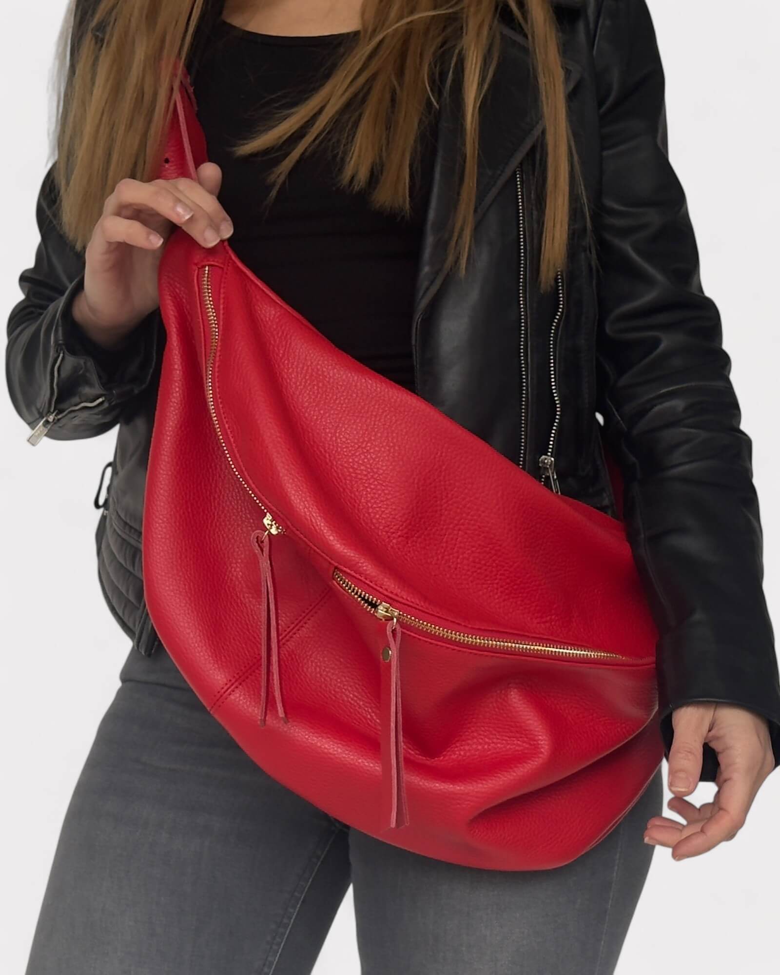 Red leather bag held by a person wearing a black jacket 