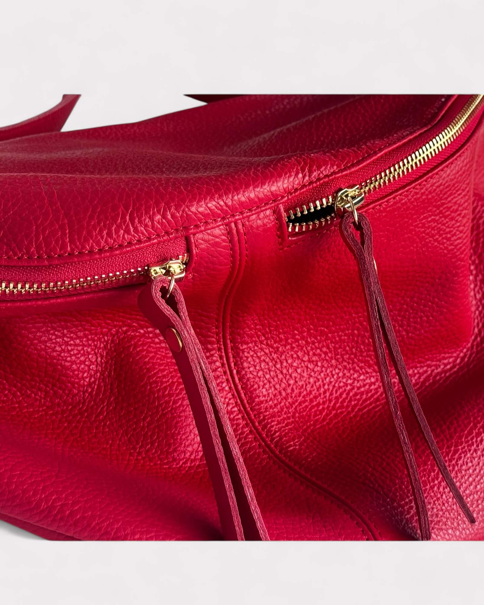Close-up of a red leather handbag with gold zipper
