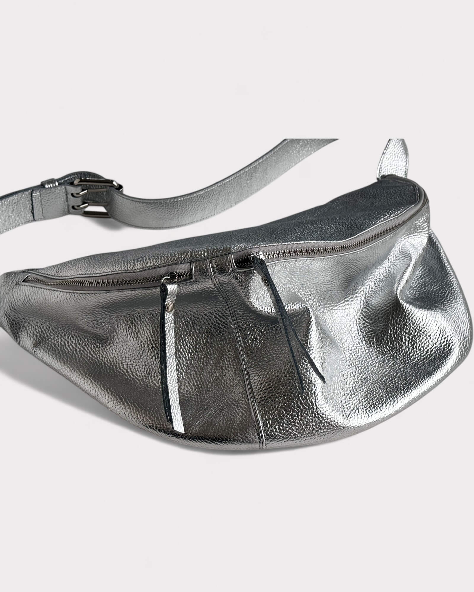 Silver metallic sling bag on a light gray background