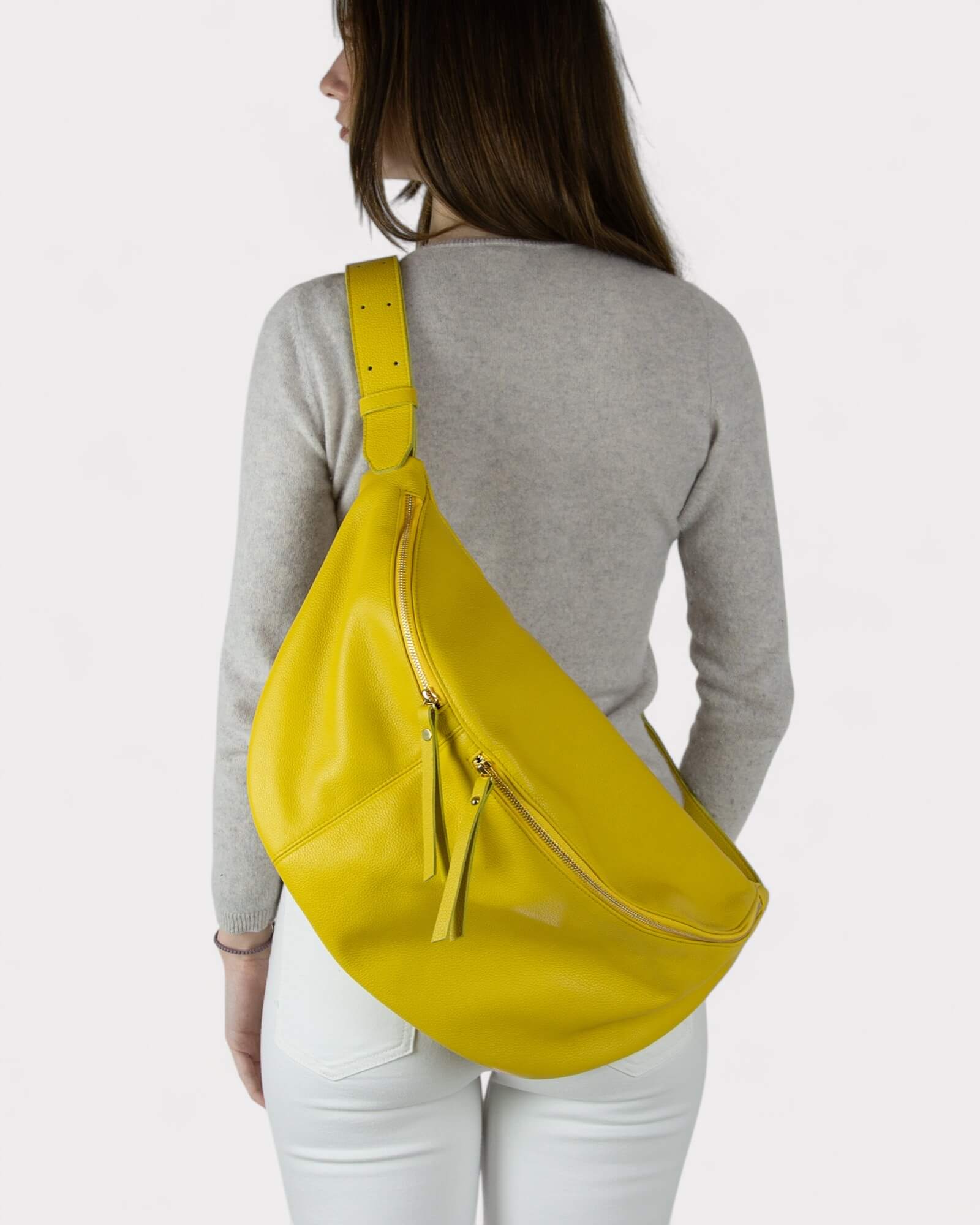 Person wearing a yellow sling bag on a plain background