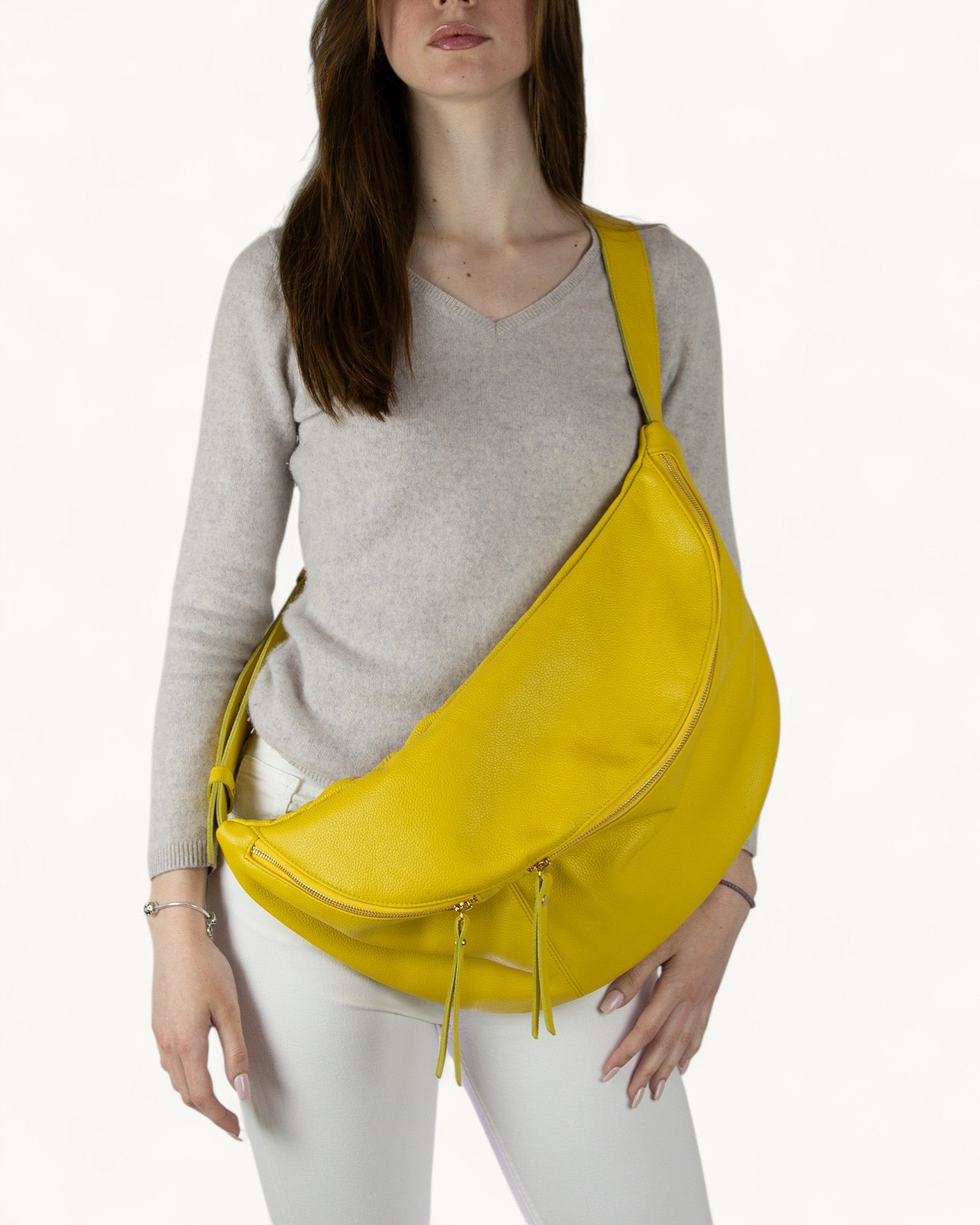 Woman wearing a mustard yellow sling bag on a white background